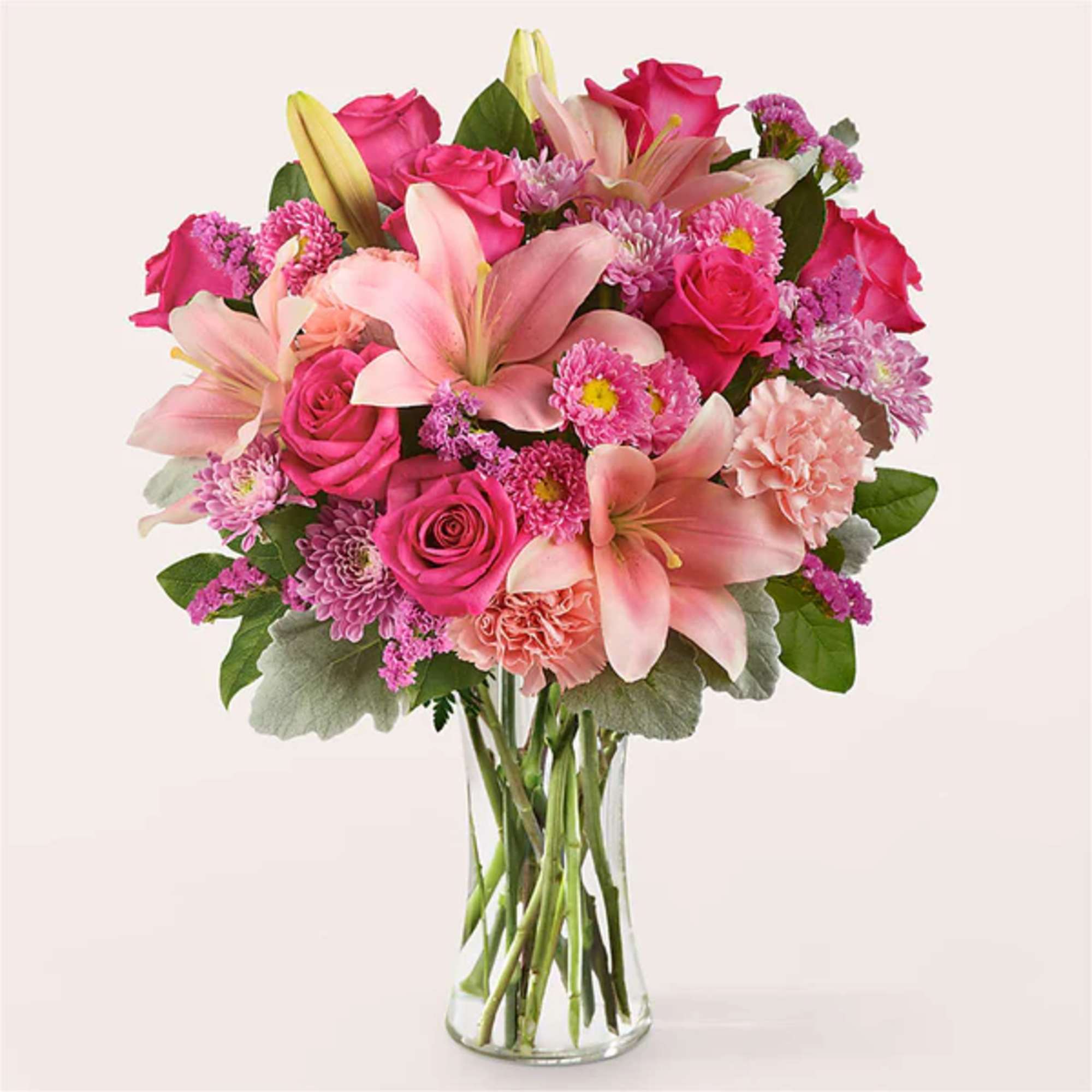 Pink roses and lilies arranged in a clear glass vase