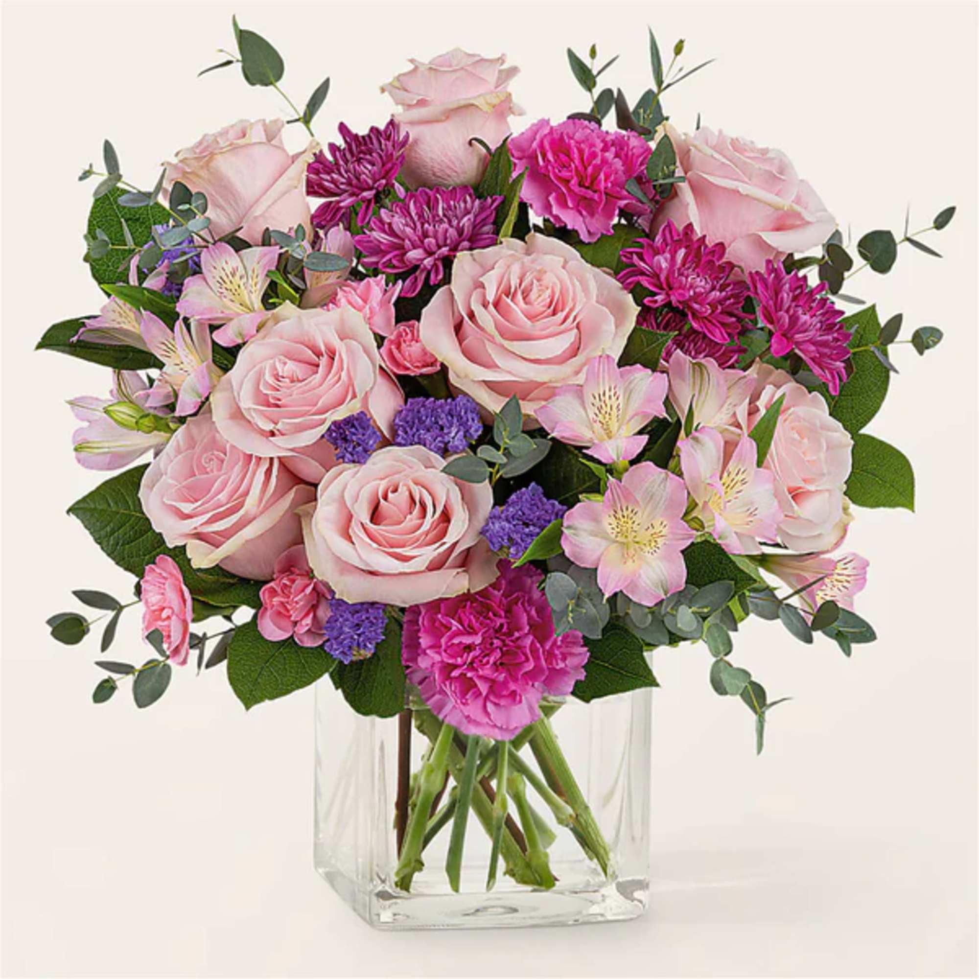 Pink roses and mixed blooms in a clear glass vase