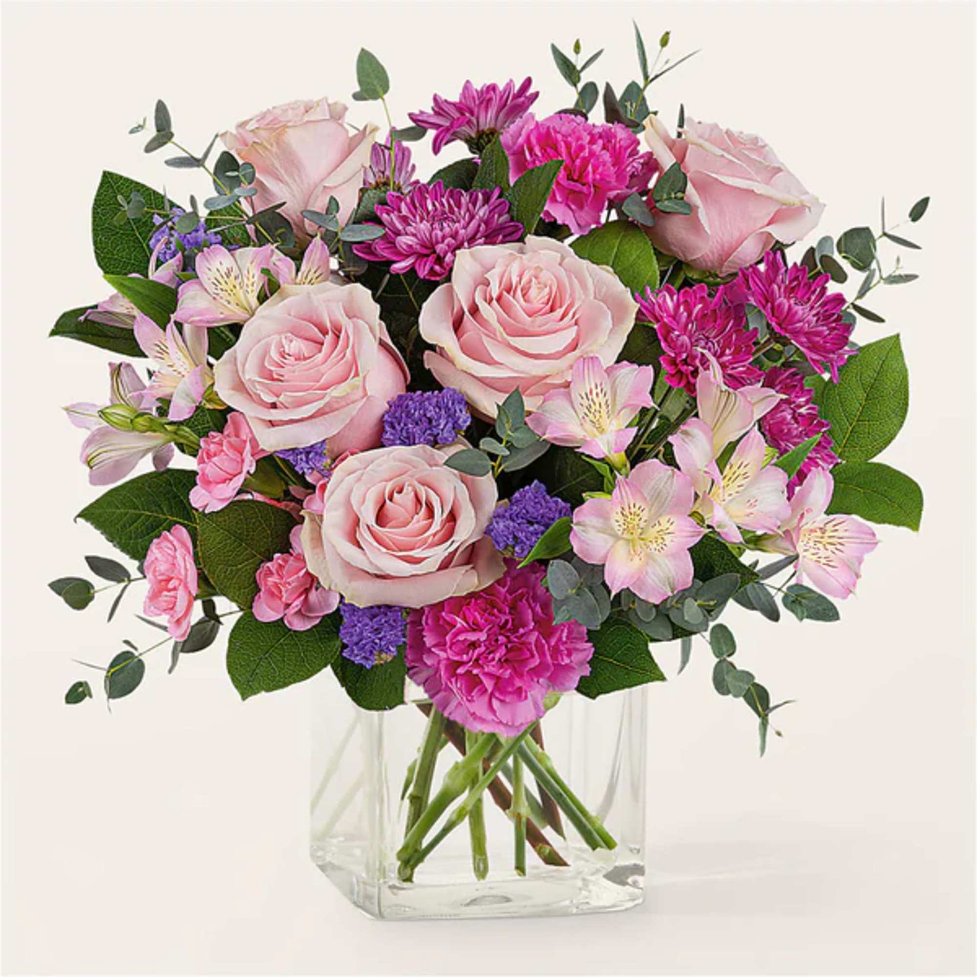 Pink roses and mixed pink-purple flowers in a clear glass vase