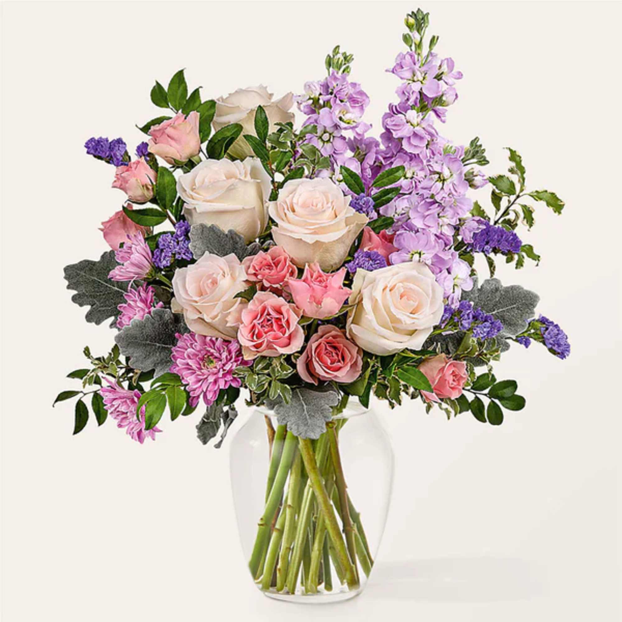 Bouquet of pink and white roses with purple flowers in a clear glass vase