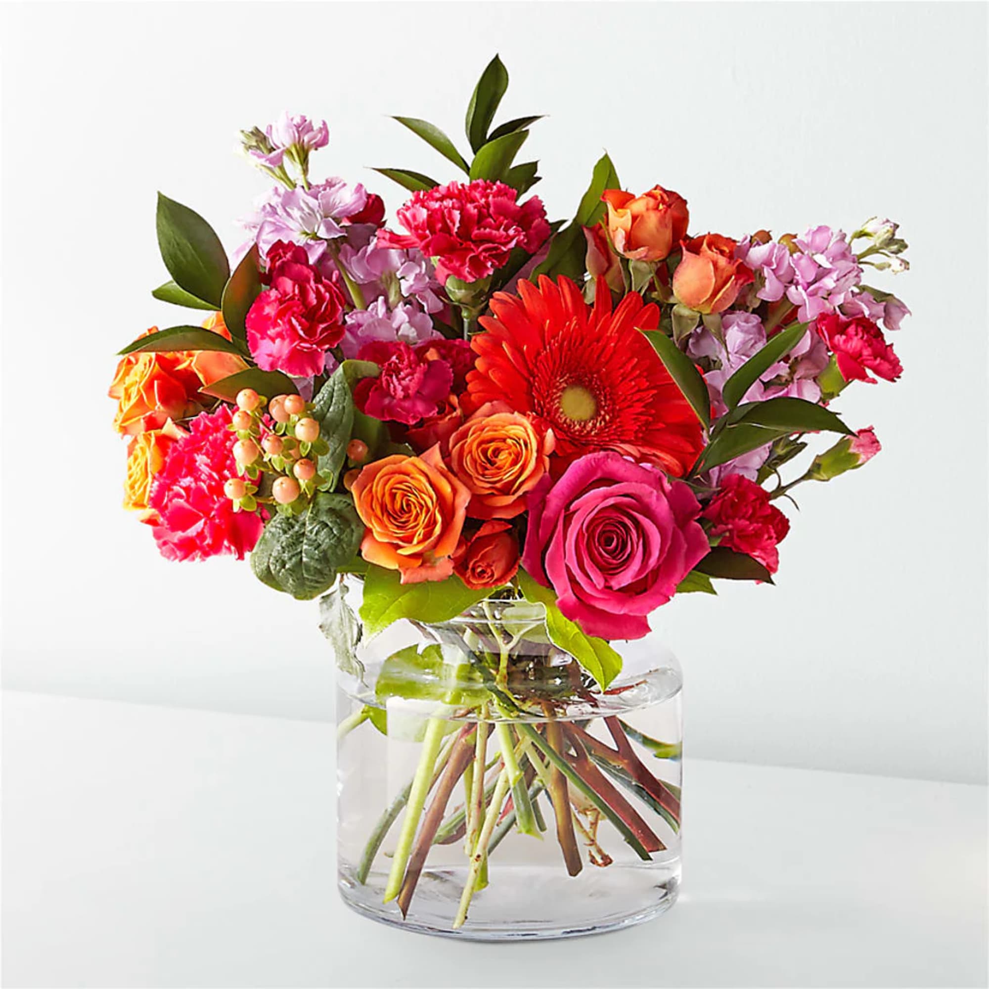 Mixed bouquet of roses, gerbera daisies, and carnations in a glass vase