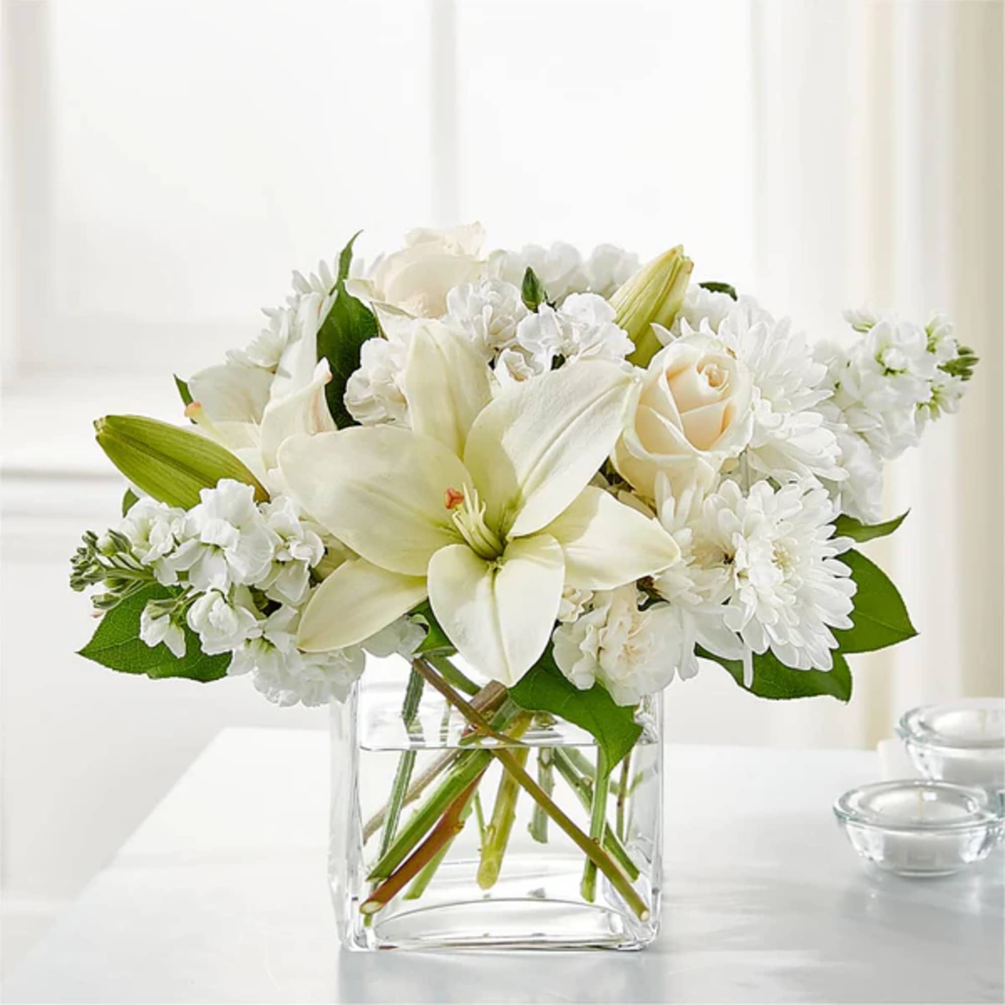 White lilies and roses in a clear glass vase