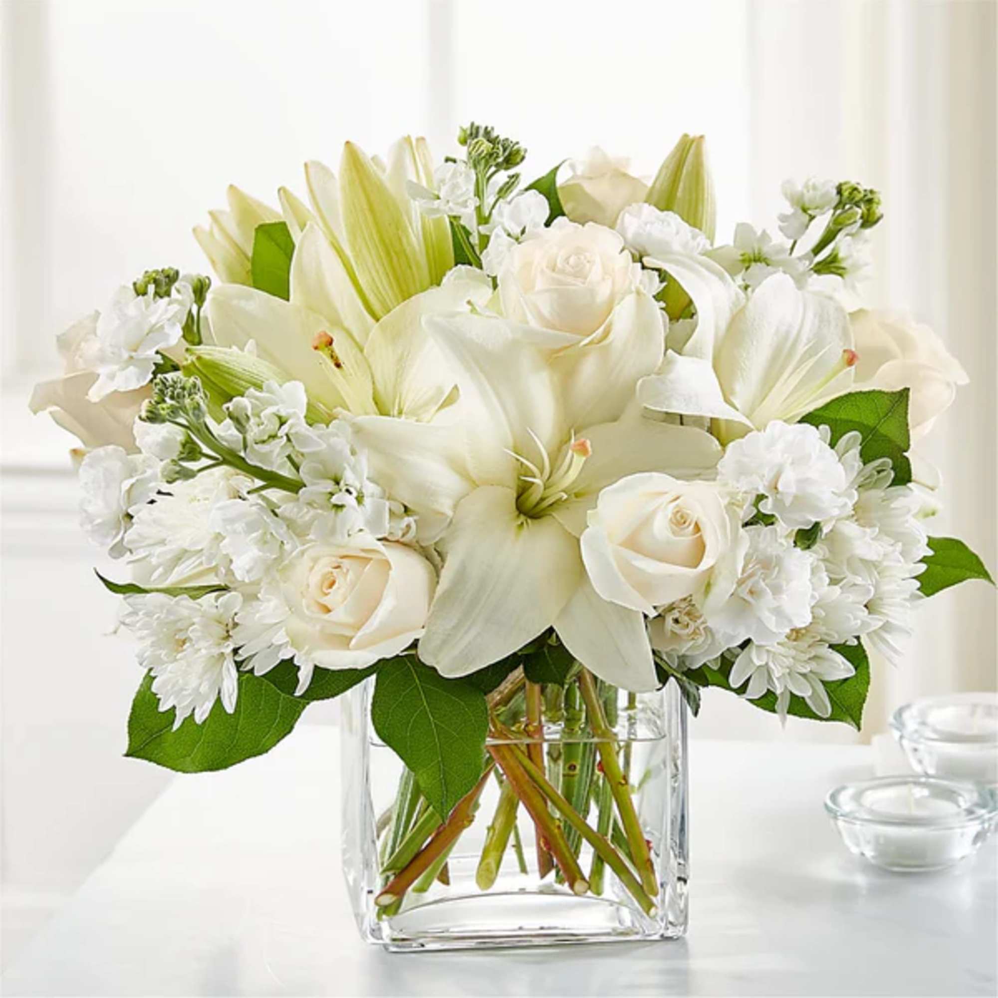White lilies and roses in a clear glass vase