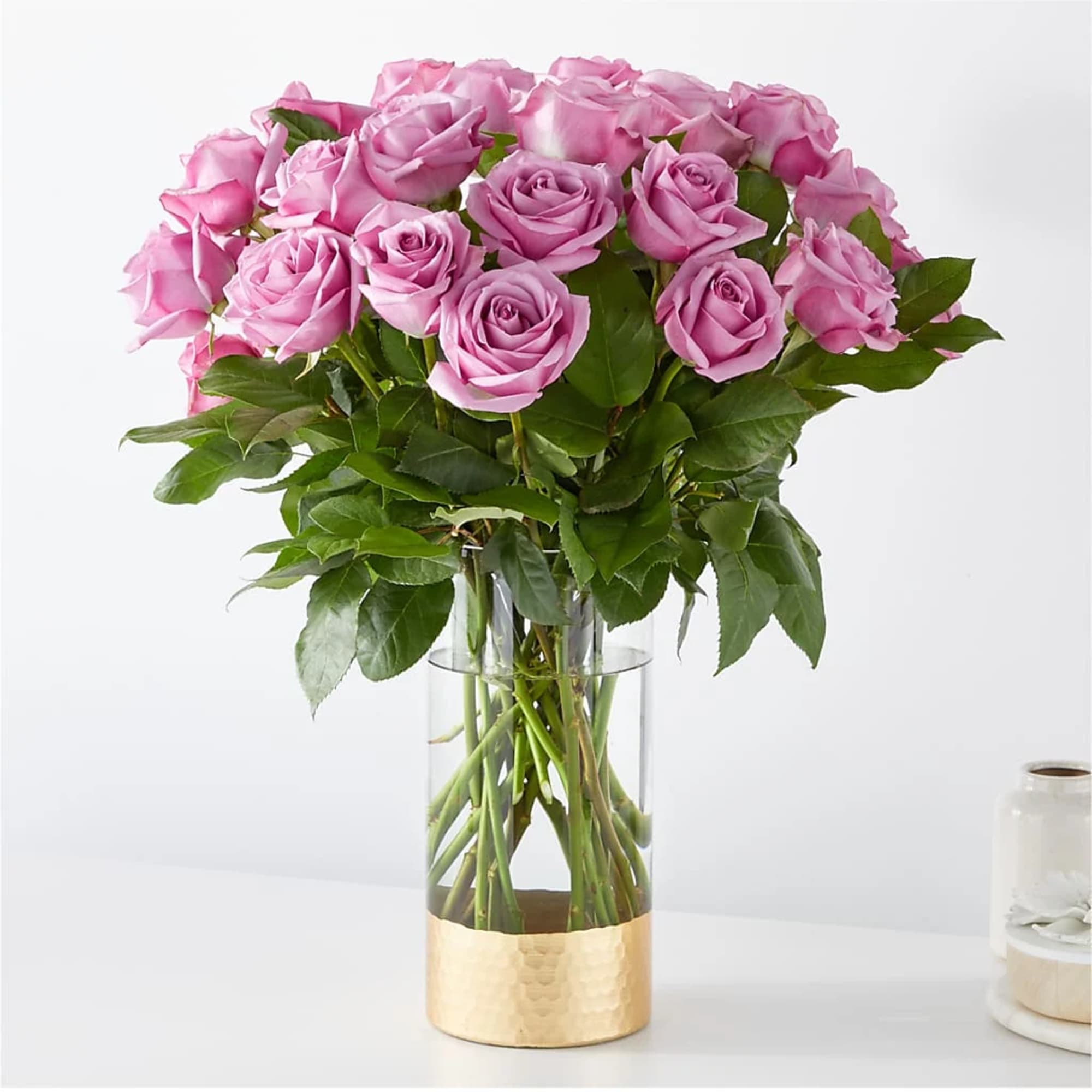 Pink roses arranged in a clear glass vase with a gold base