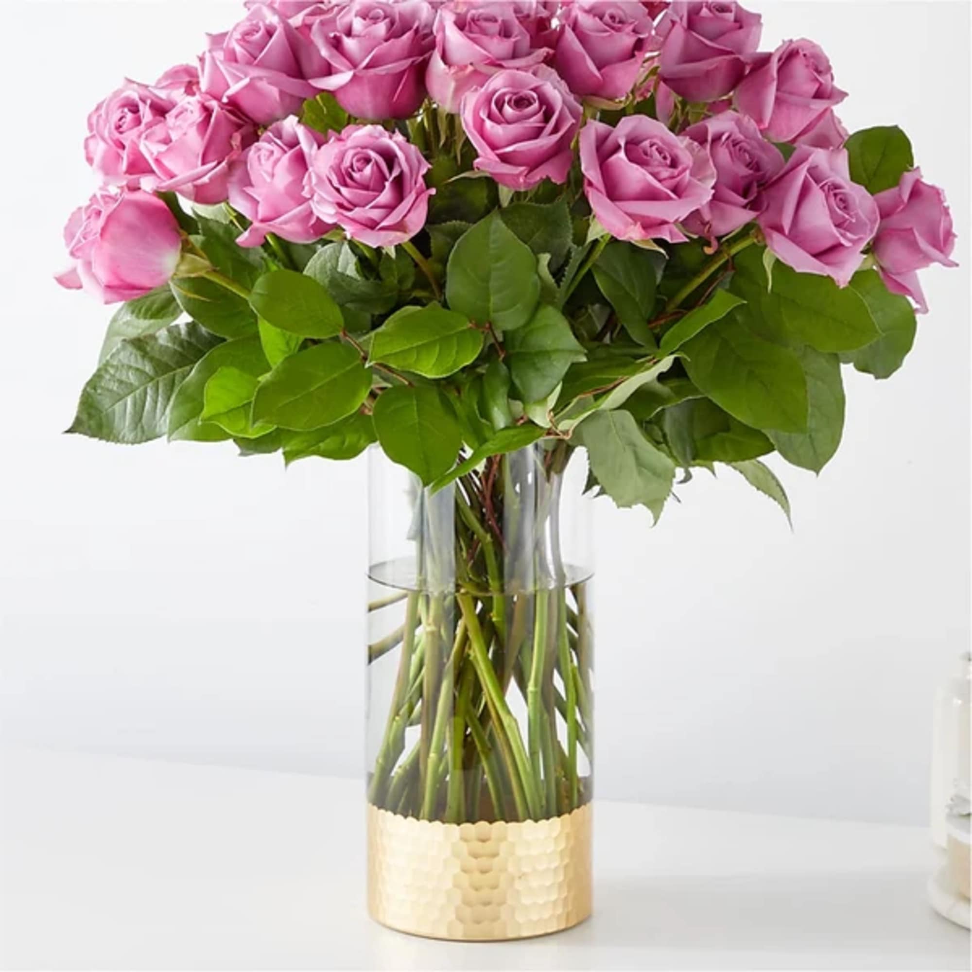 Pink roses arranged in a clear glass vase with a gold base