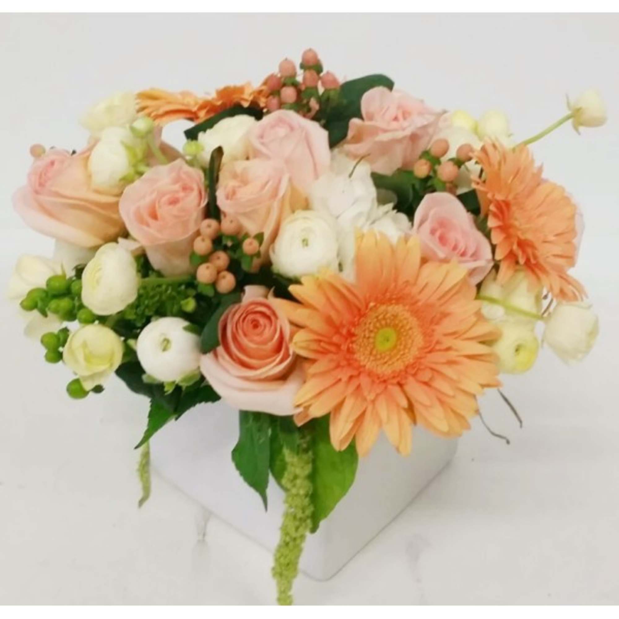 Peach and white bouquet with gerbera daisies and roses in a white container