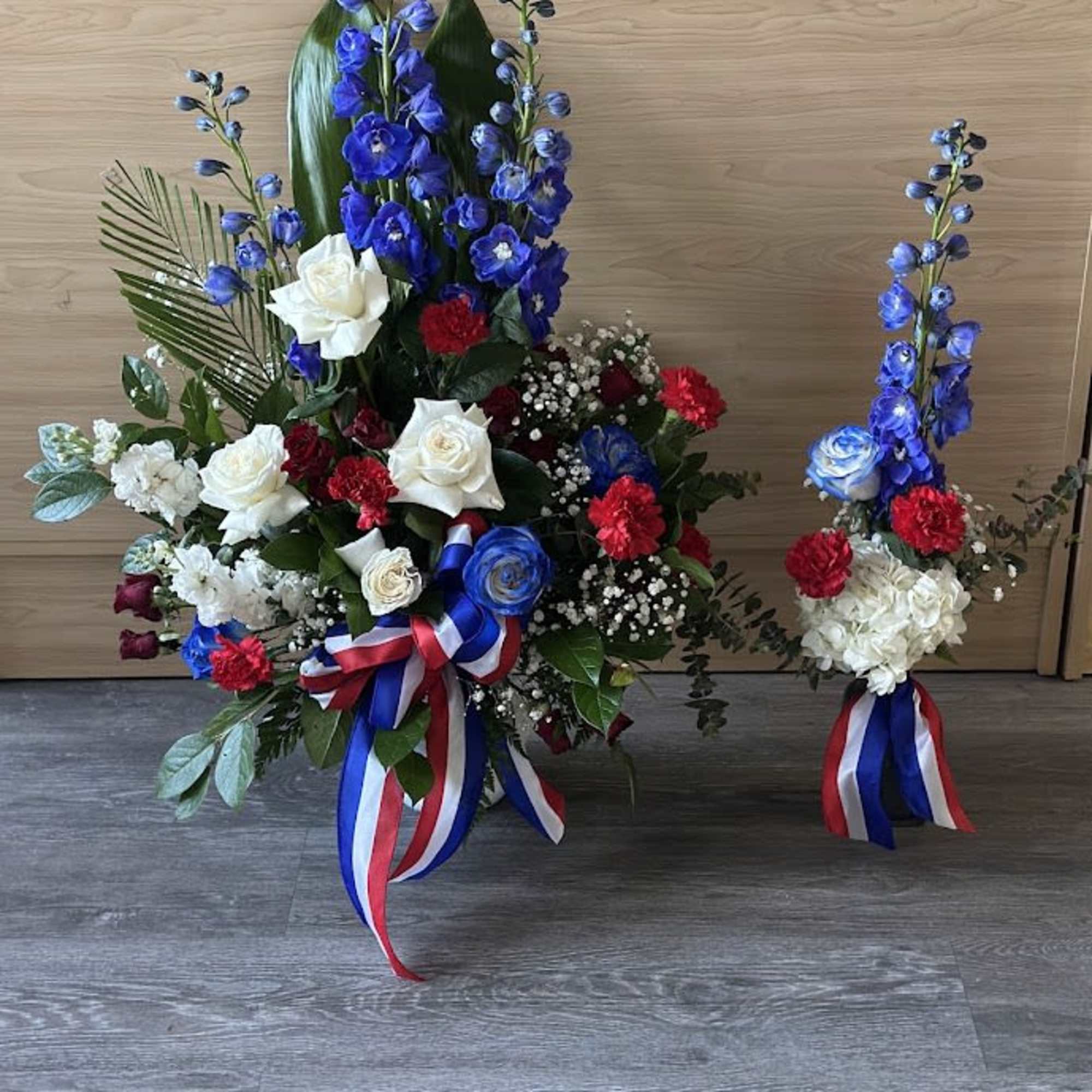 Blue, white, and red floral arrangements with ribbon accents