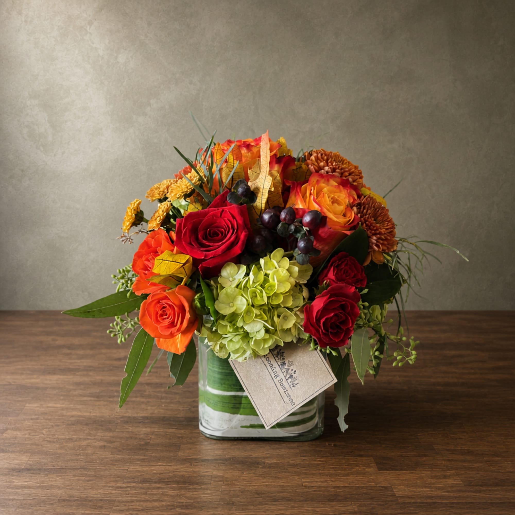 Mixed bouquet of roses, hydrangea, and mums in a glass vase