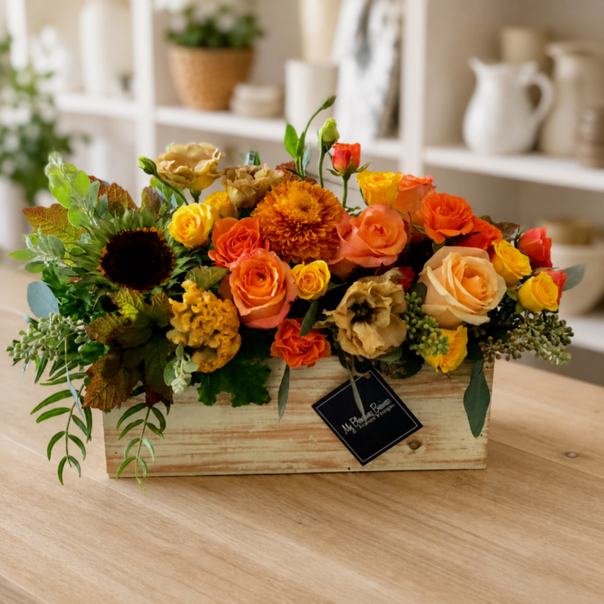Mixed orange and yellow flower arrangement in a wooden box