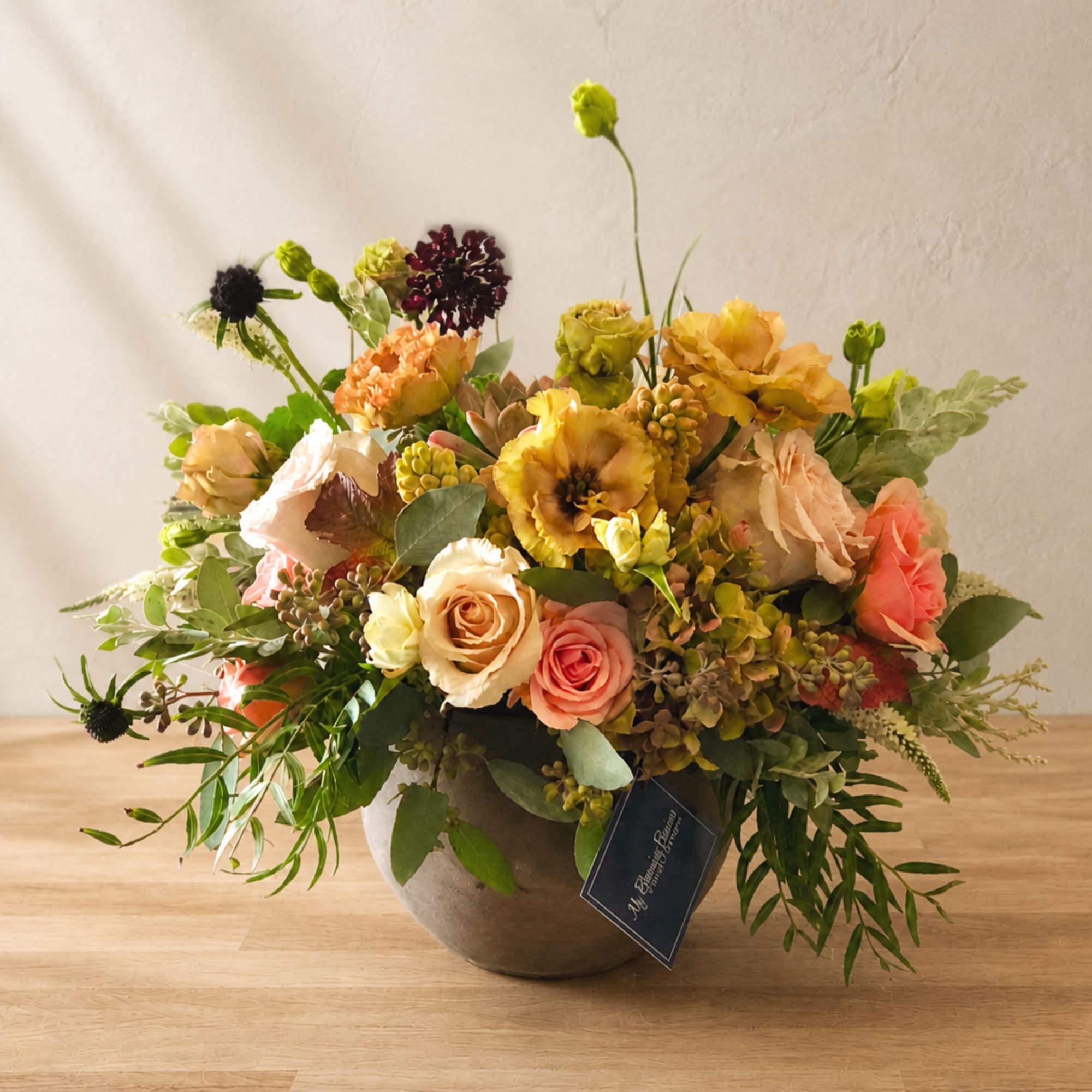 Mixed floral arrangement in a round vase with peach, yellow, and coral blooms