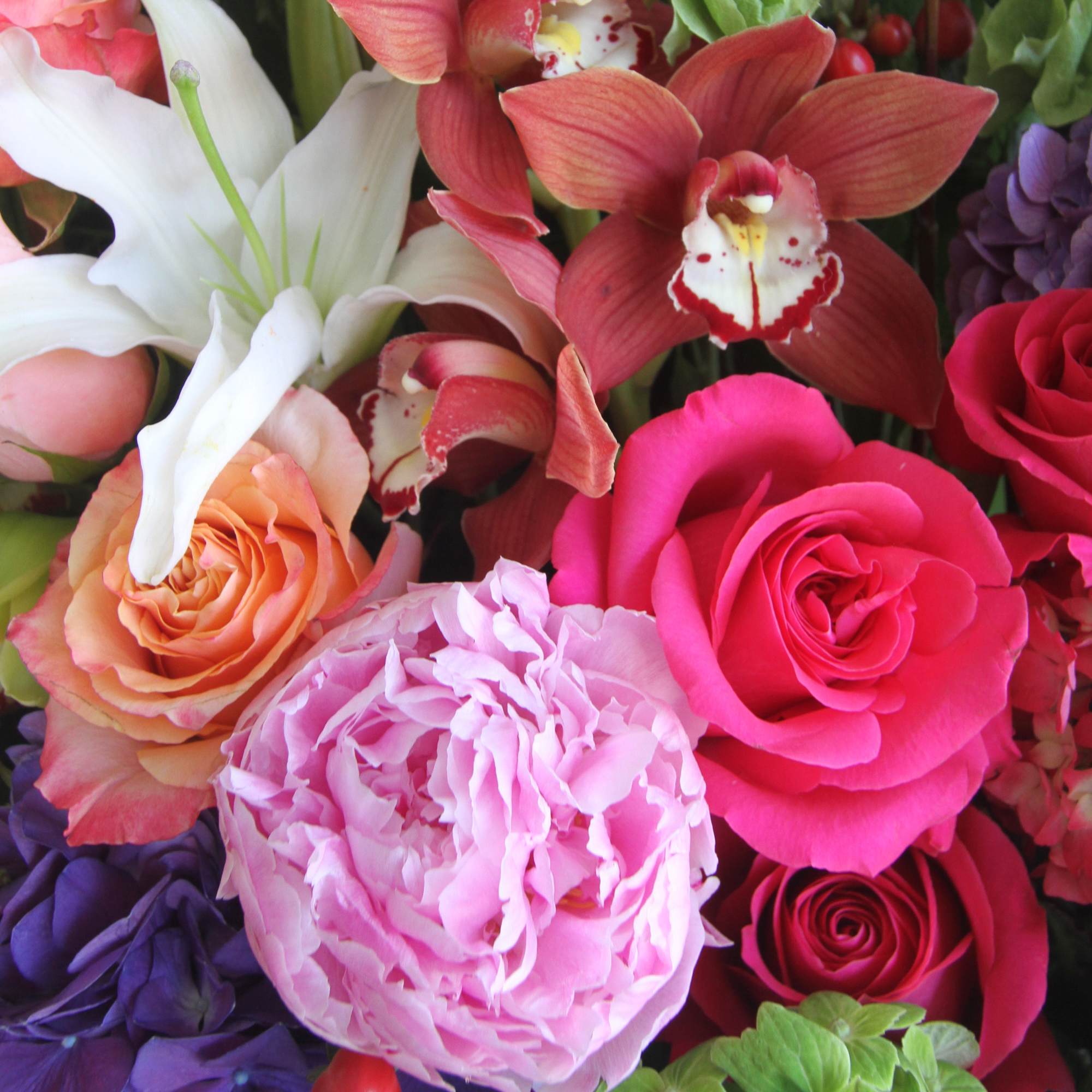 Close-up bouquet with pink roses, lilies, and orchids