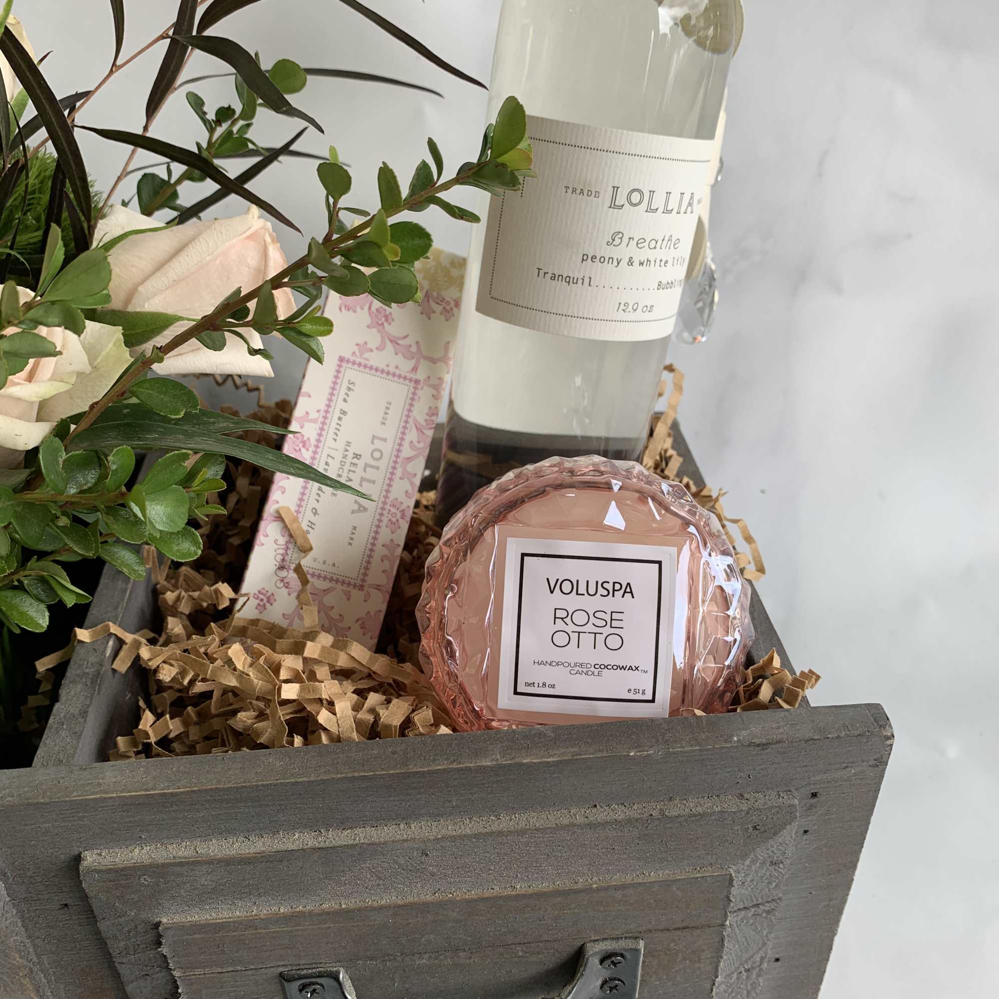 Gift basket with roses, a candle, and a bottle of bath product