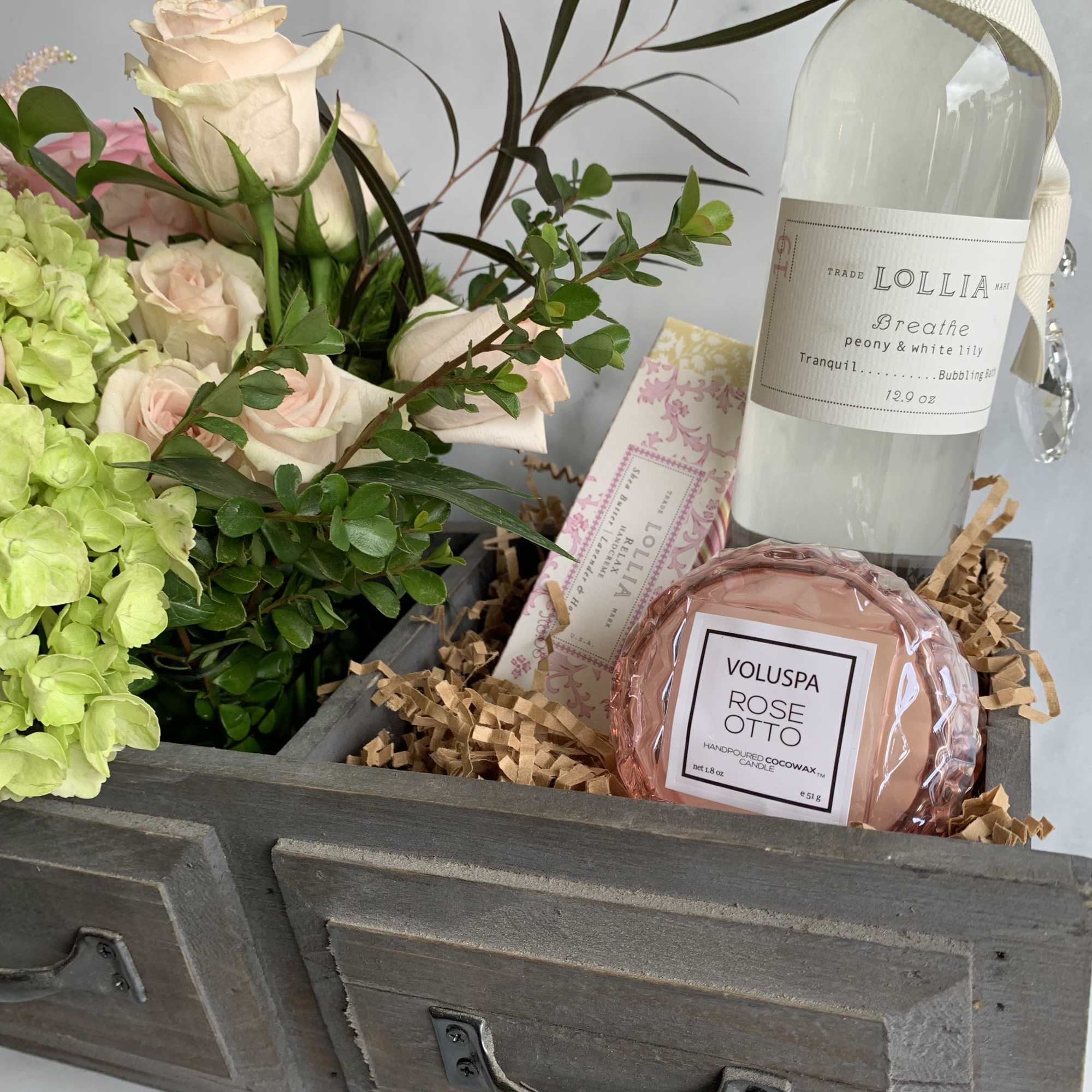 Gift box with pale roses, green hydrangea, and candles