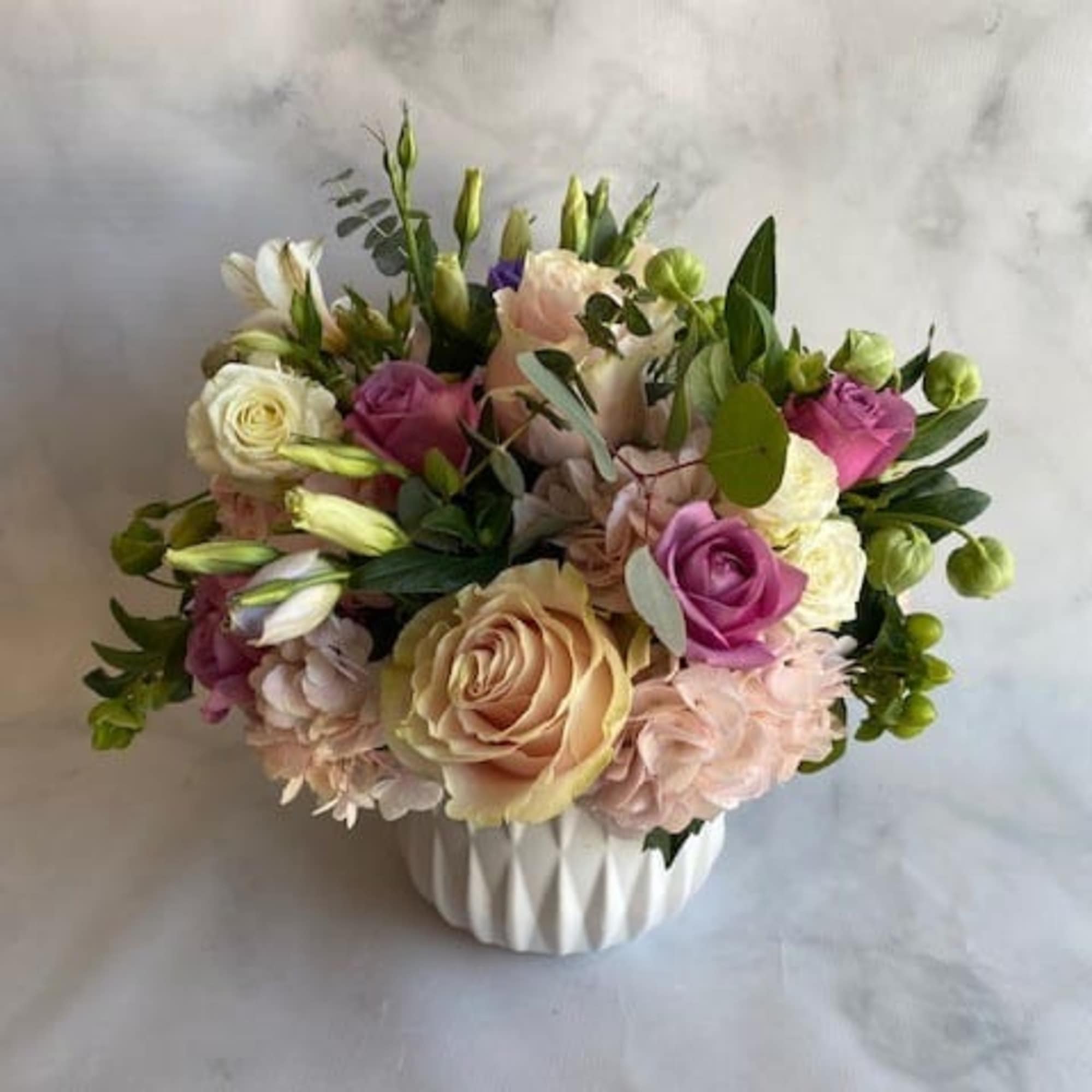 Mixed bouquet of roses and lisianthus in a white vase