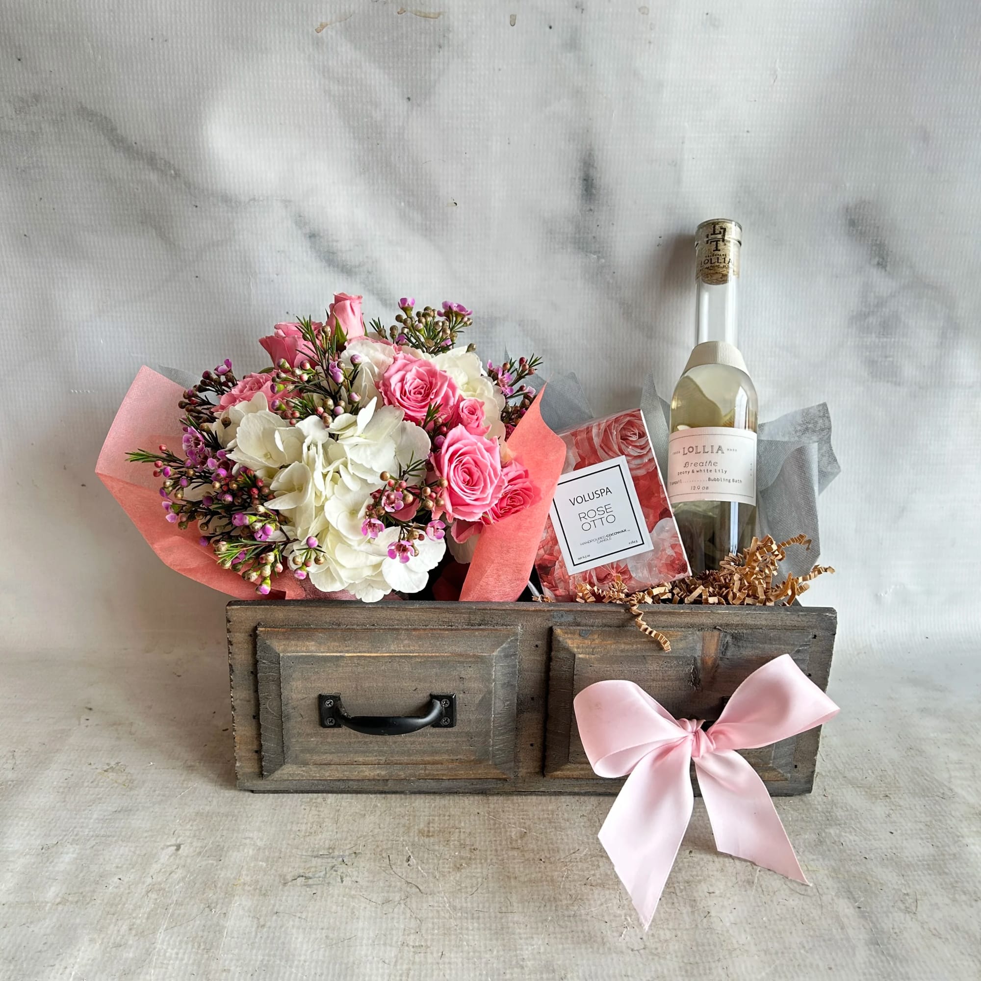 Pink and white flower bouquet with a wine bottle and candle in a wooden gift box