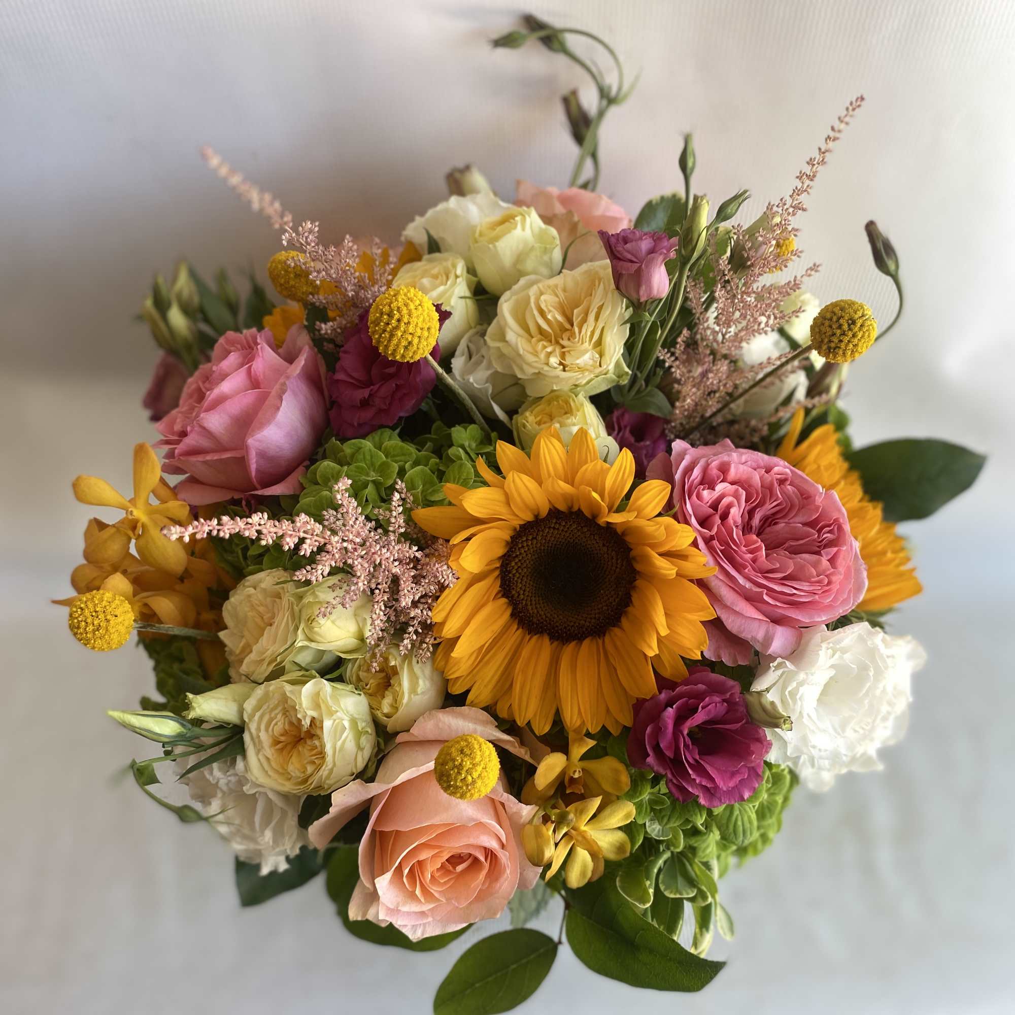 Mixed bouquet with a sunflower, pink roses, and cream blooms