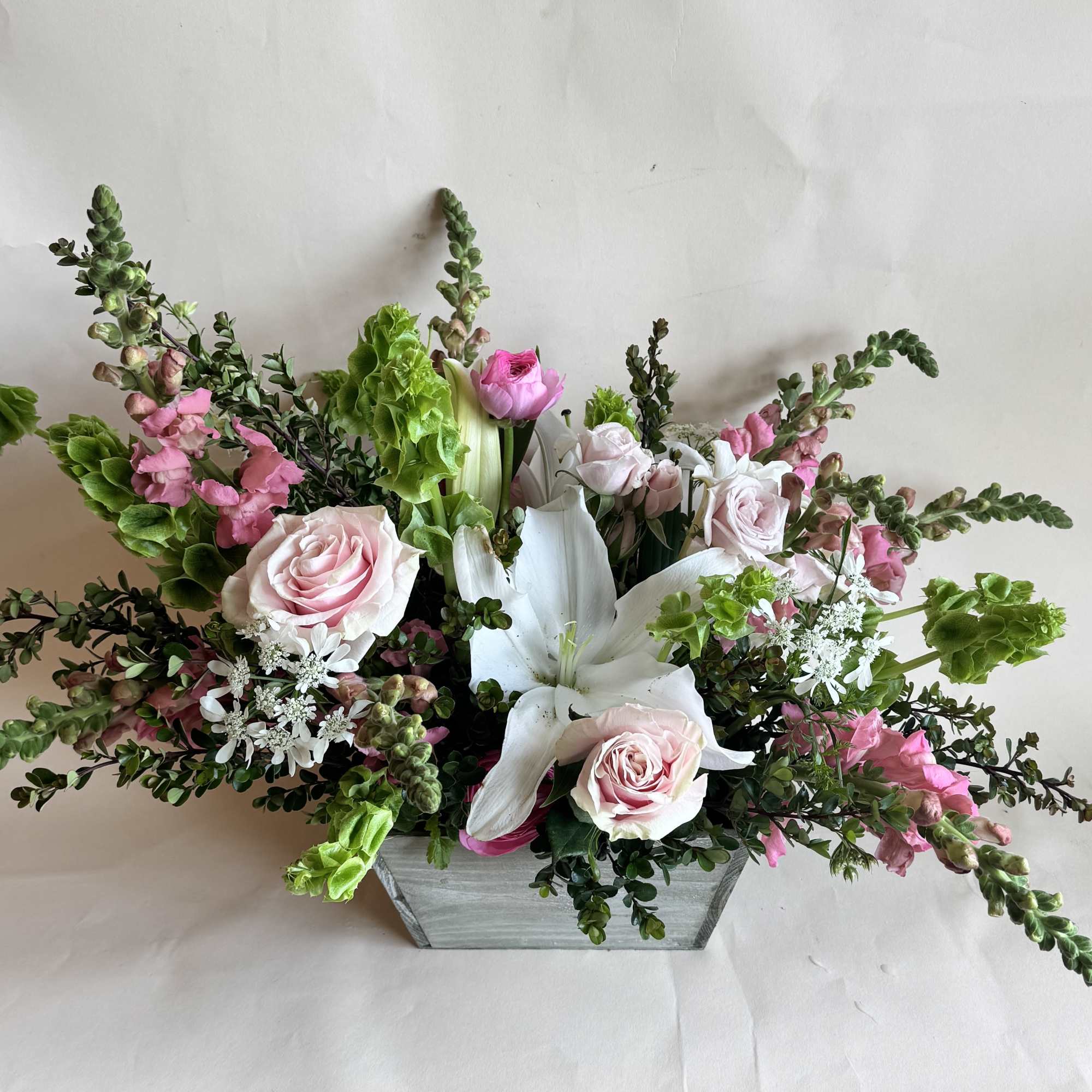 Pink roses and white lilies in a rectangular wooden container