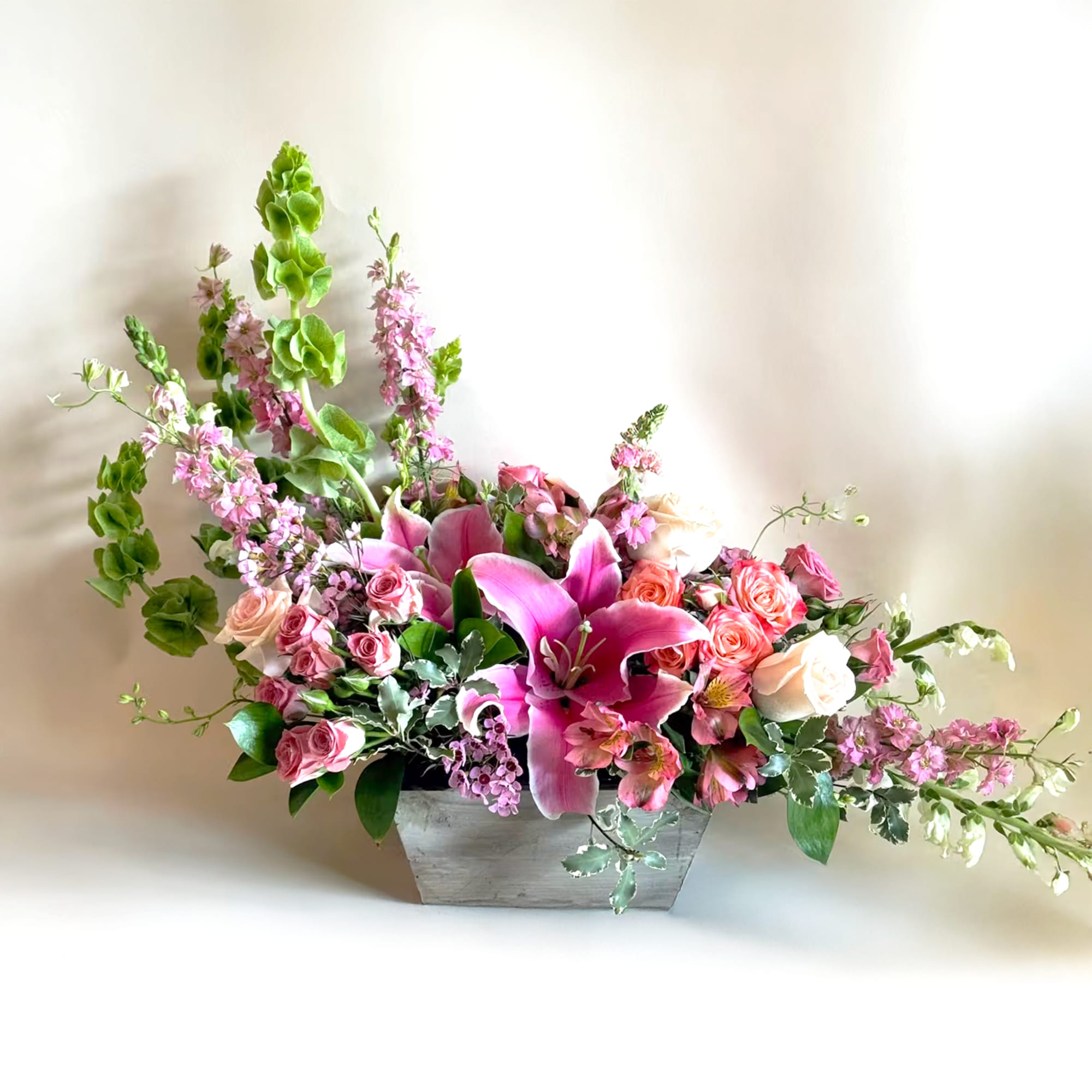 Pink lilies and roses in a gray rectangular container