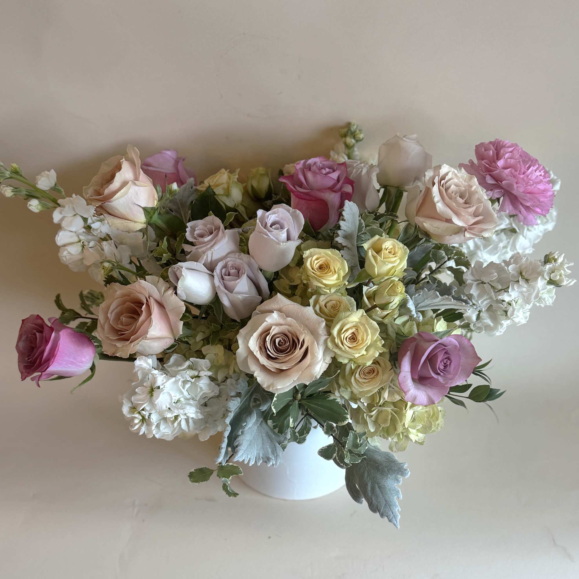 Mixed roses and white blooms arranged in a white vase