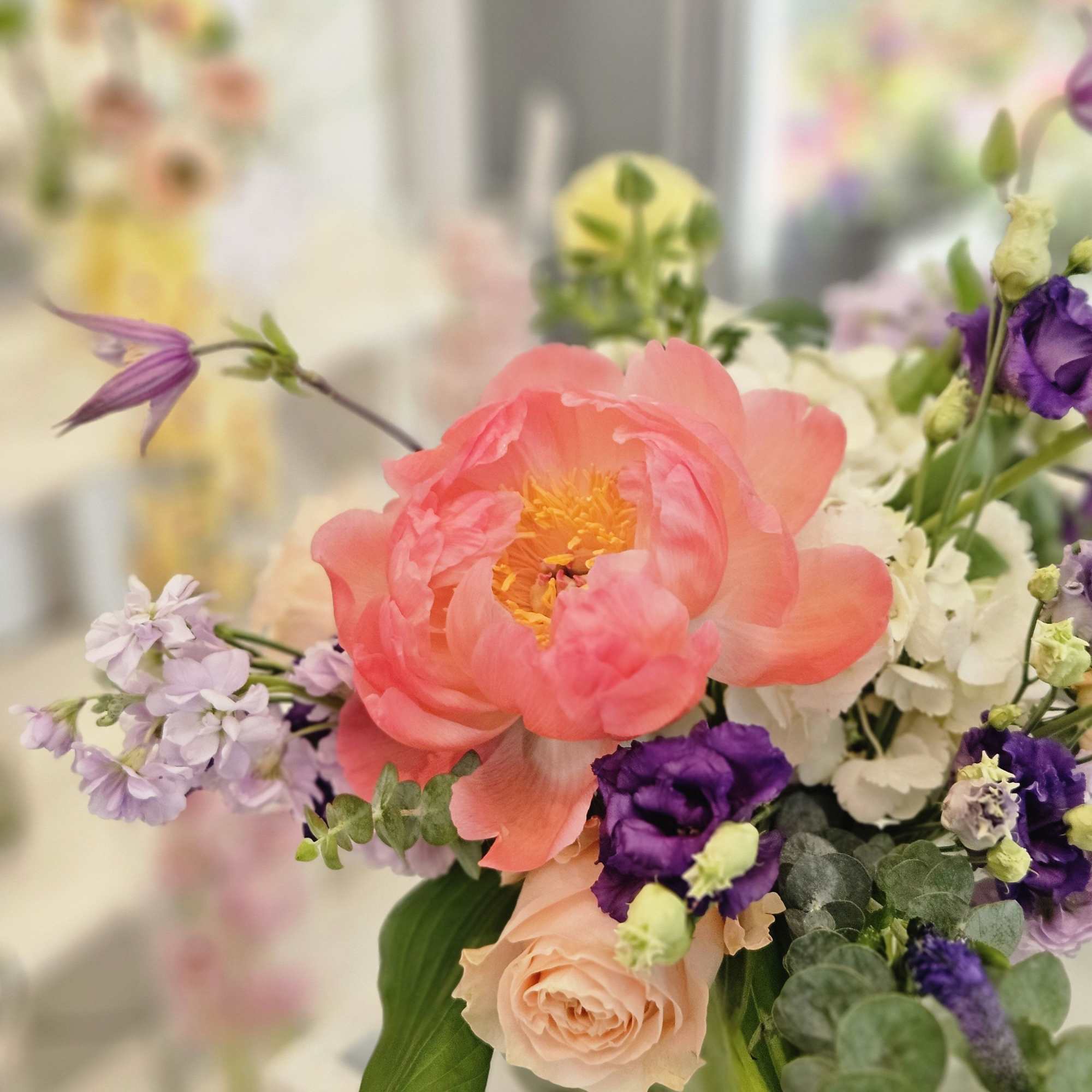 Pink peony bouquet with purple and white flowers in a vase