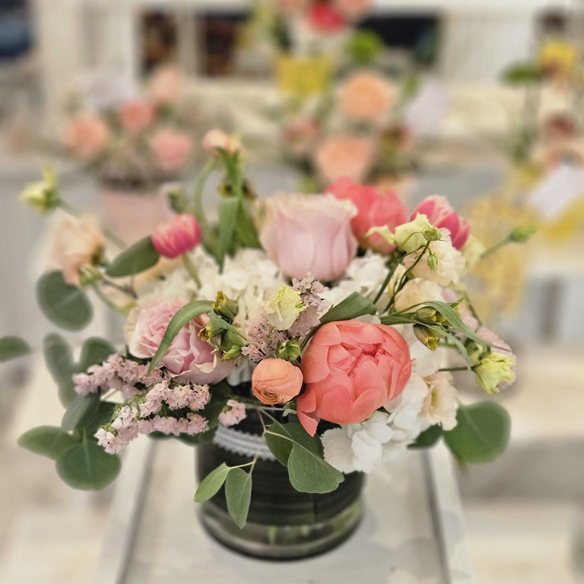 Pink and peach floral arrangement in a dark vase