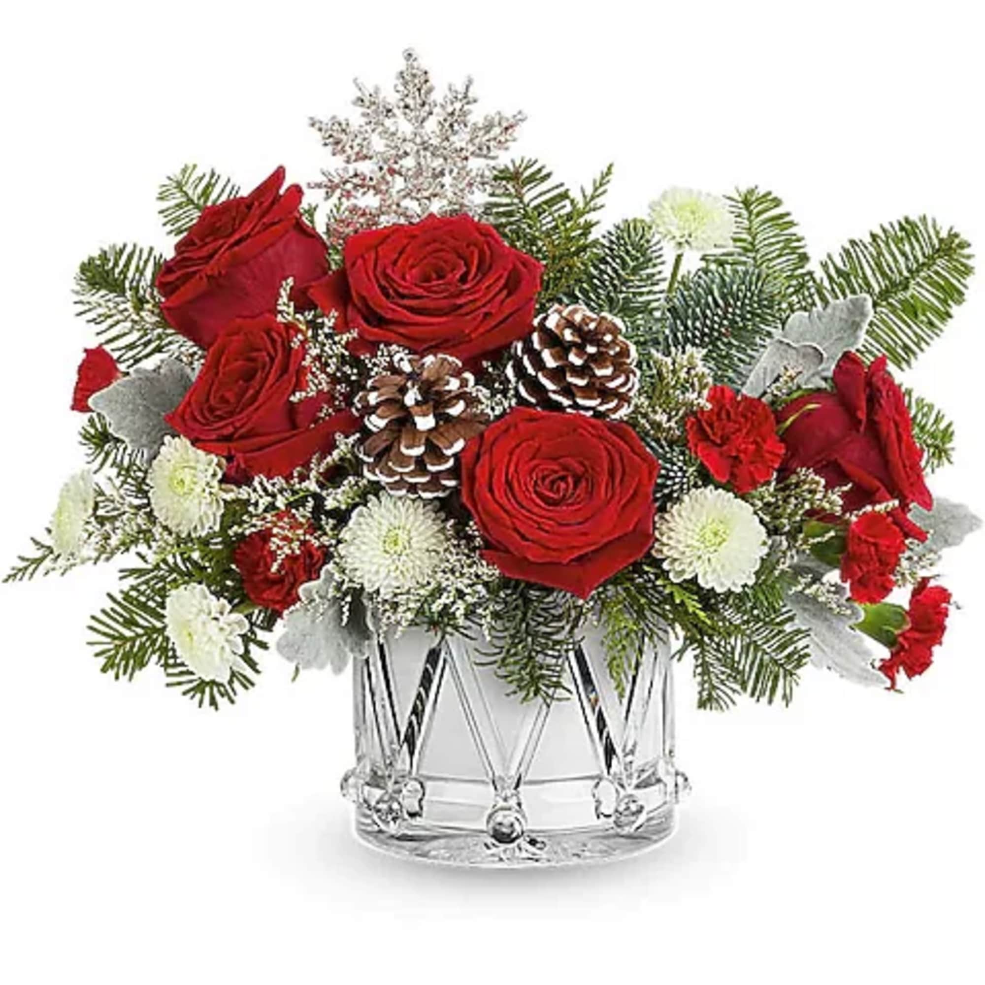 Red roses and white flowers in a clear glass vase with pinecones