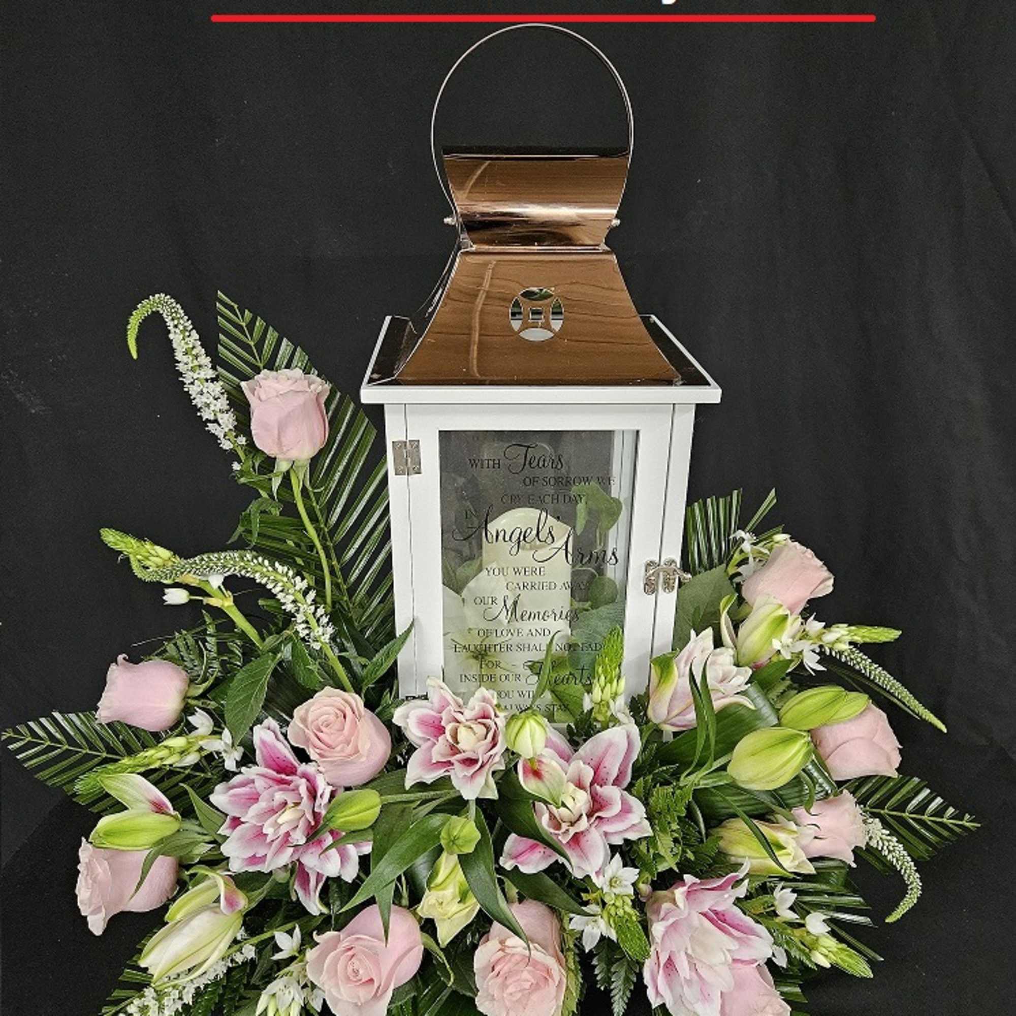 Pink and white floral arrangement around a white memorial lantern
