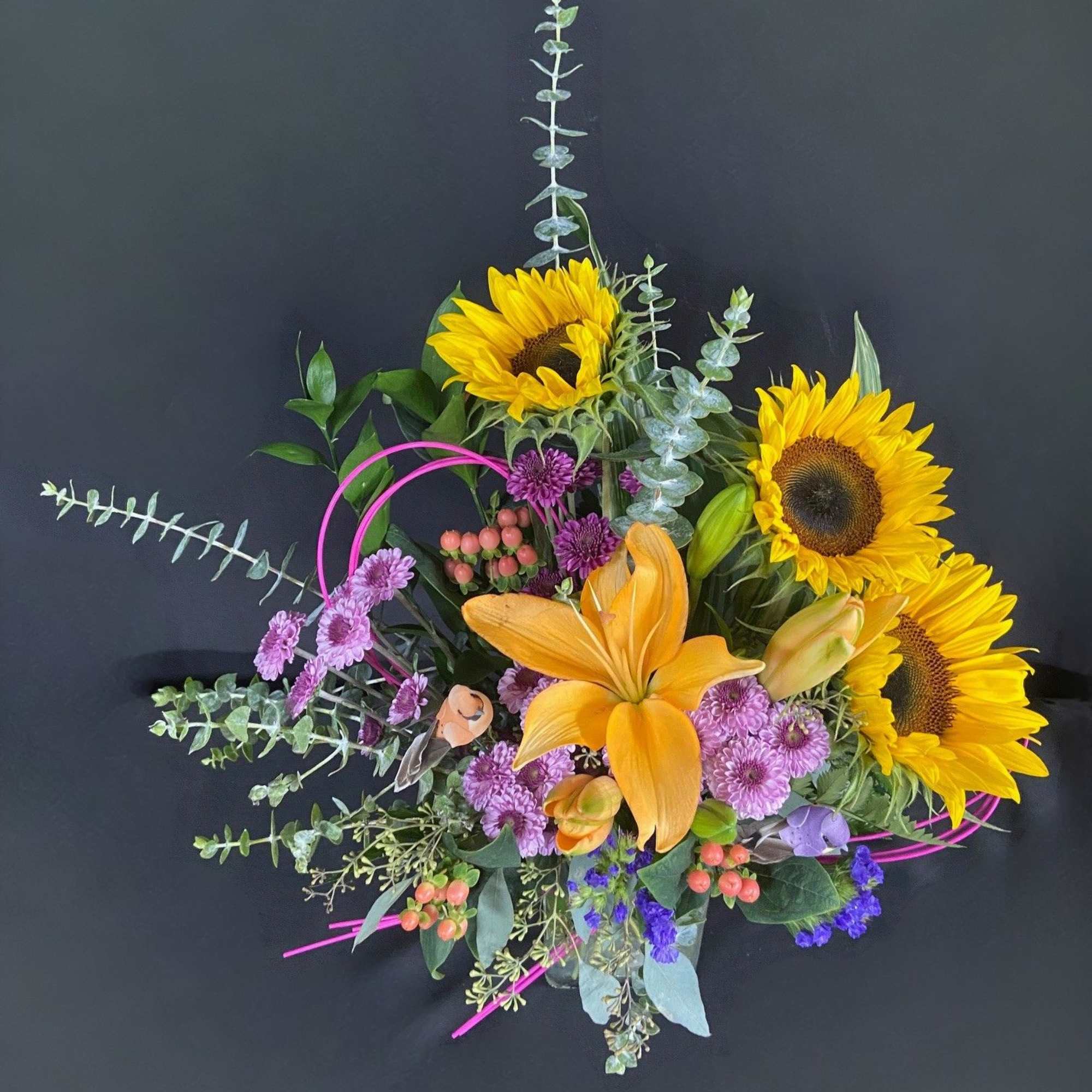 Mixed bouquet with sunflowers, an orange lily, and purple blooms