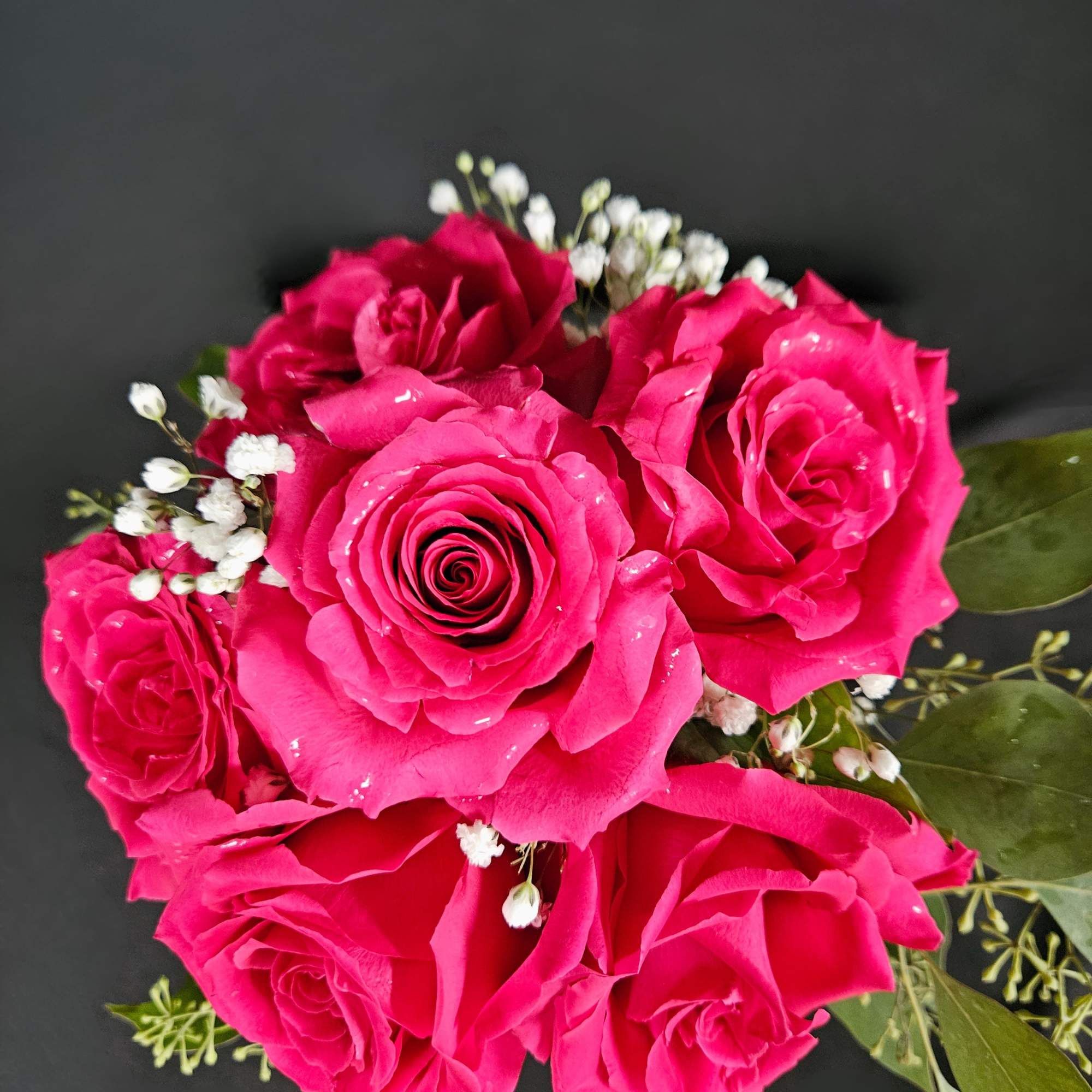 Bouquet of bright pink roses with small white filler flowers