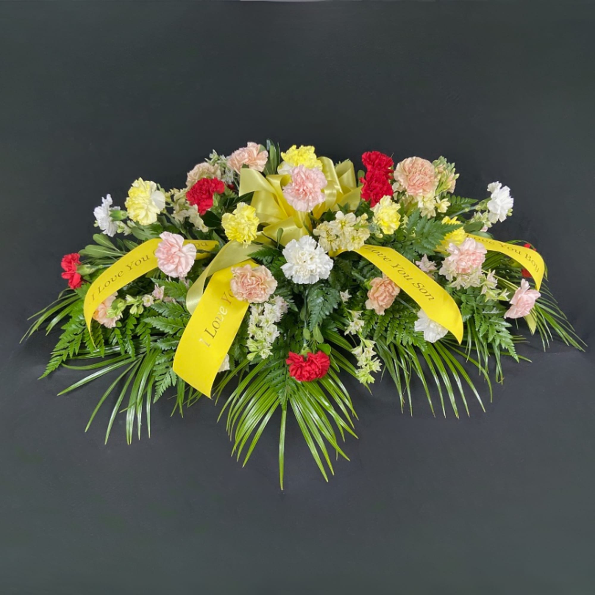 Sympathy floral spray with carnations and yellow ribbons