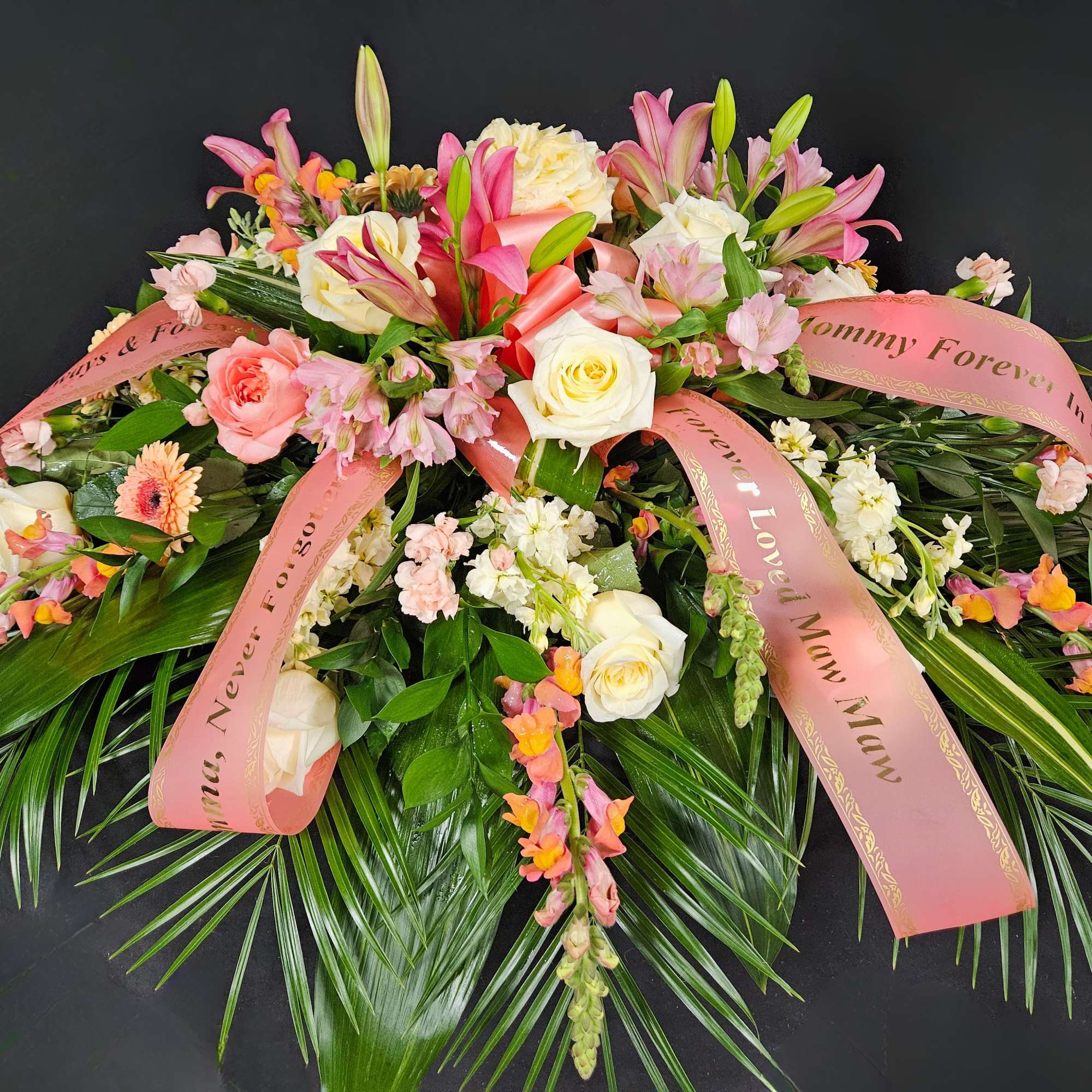 Pink and white floral spray with ribbons on a dark background