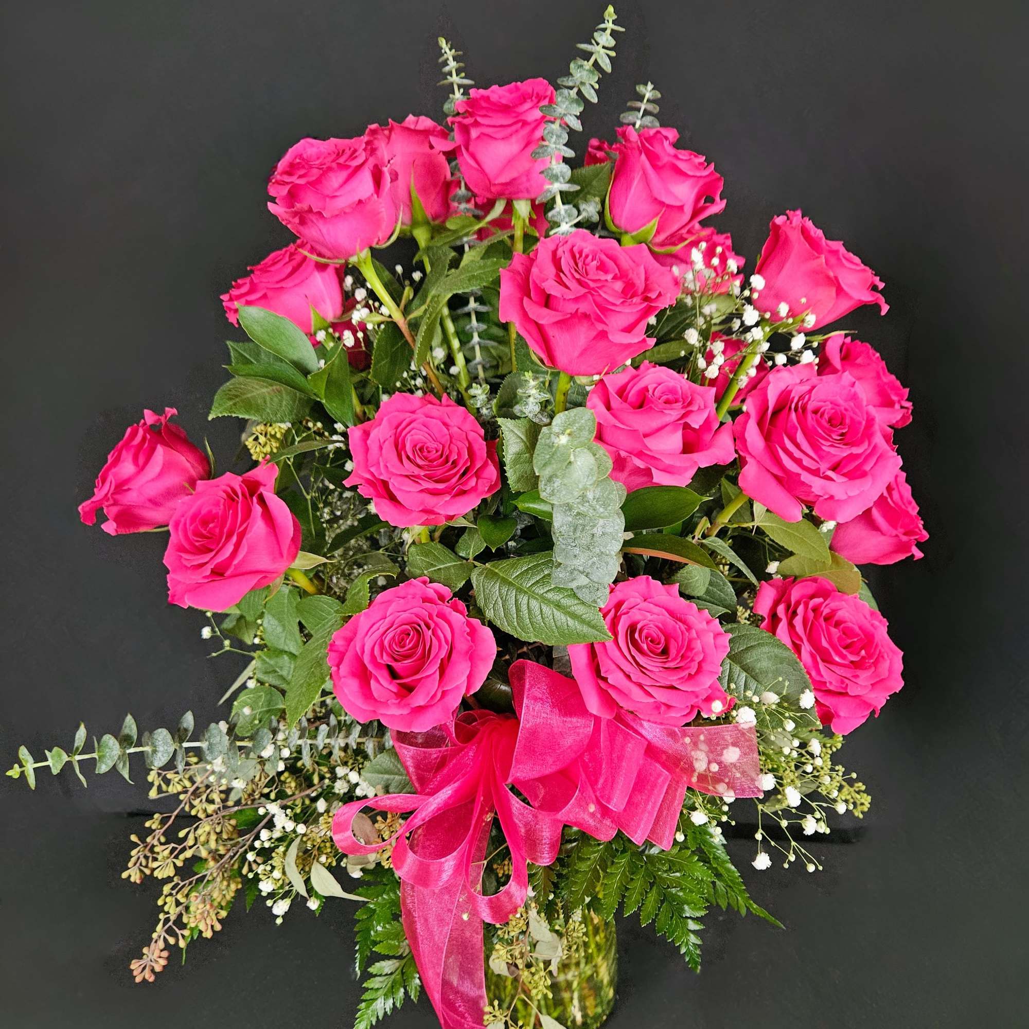 Bouquet of bright pink roses with a ribbon in a glass vase