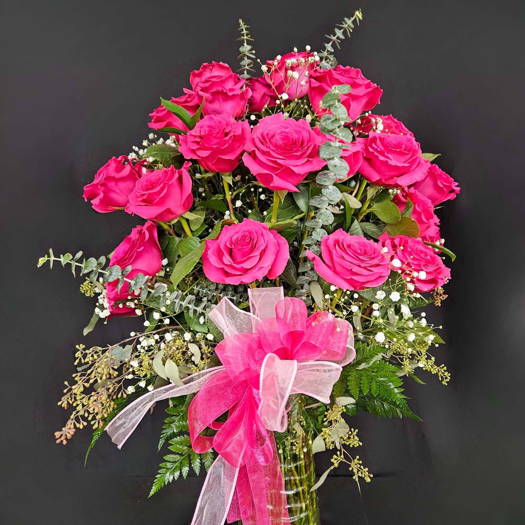 Hot pink roses in a glass vase with a pink ribbon bow