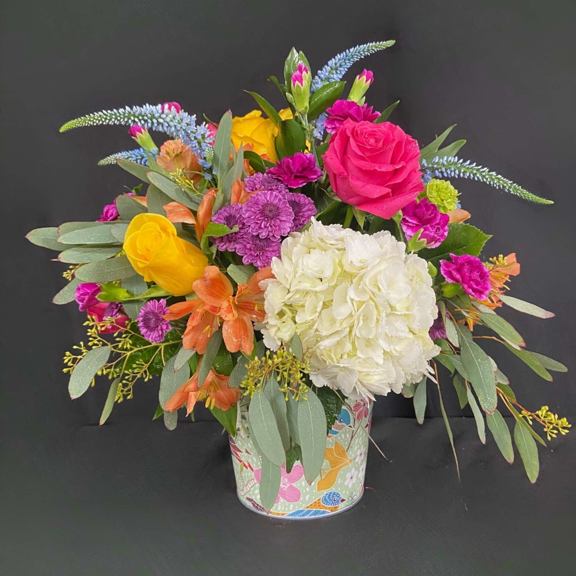 Colorful mixed bouquet in a patterned tin container