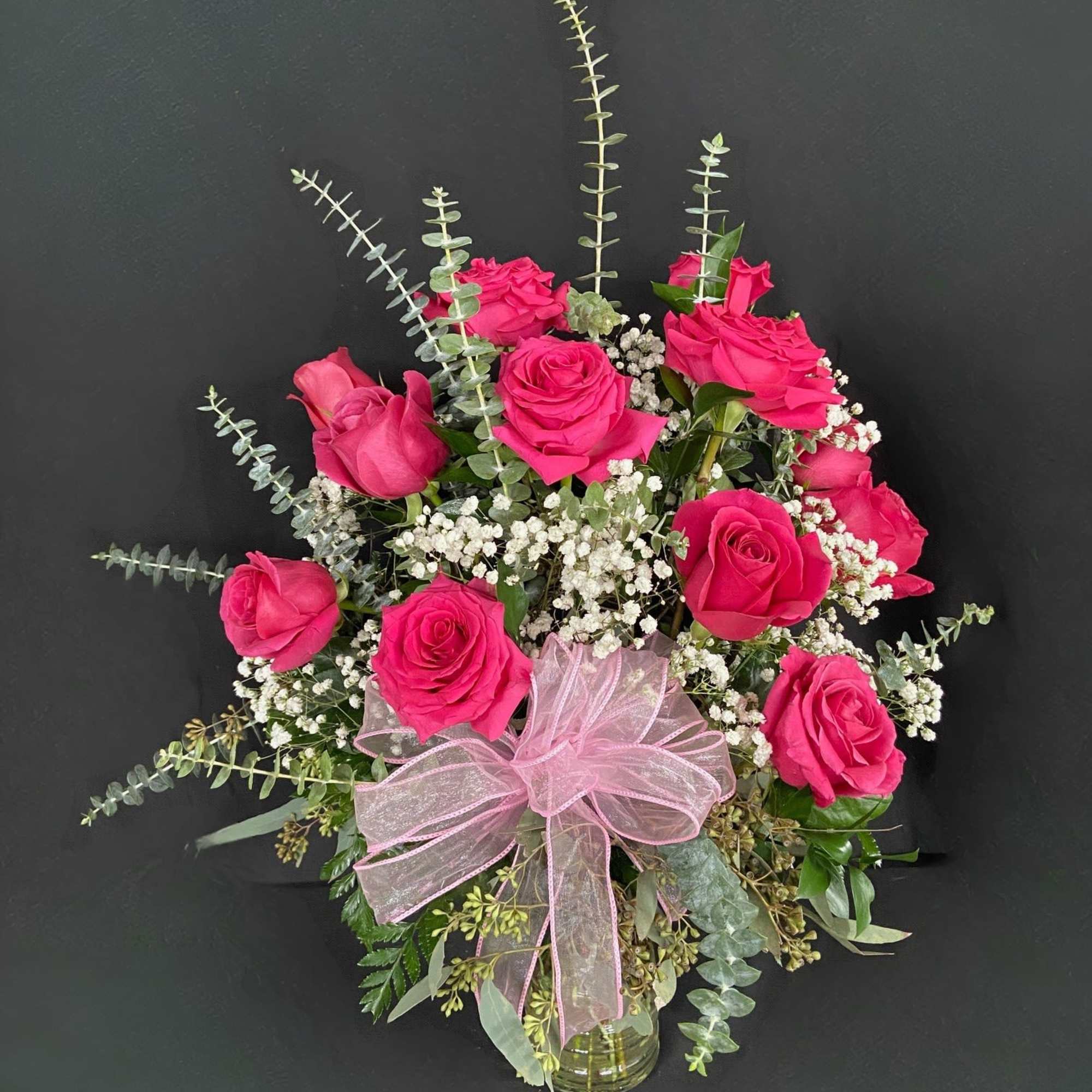 Pink rose bouquet with baby's breath in a glass vase and pink ribbon