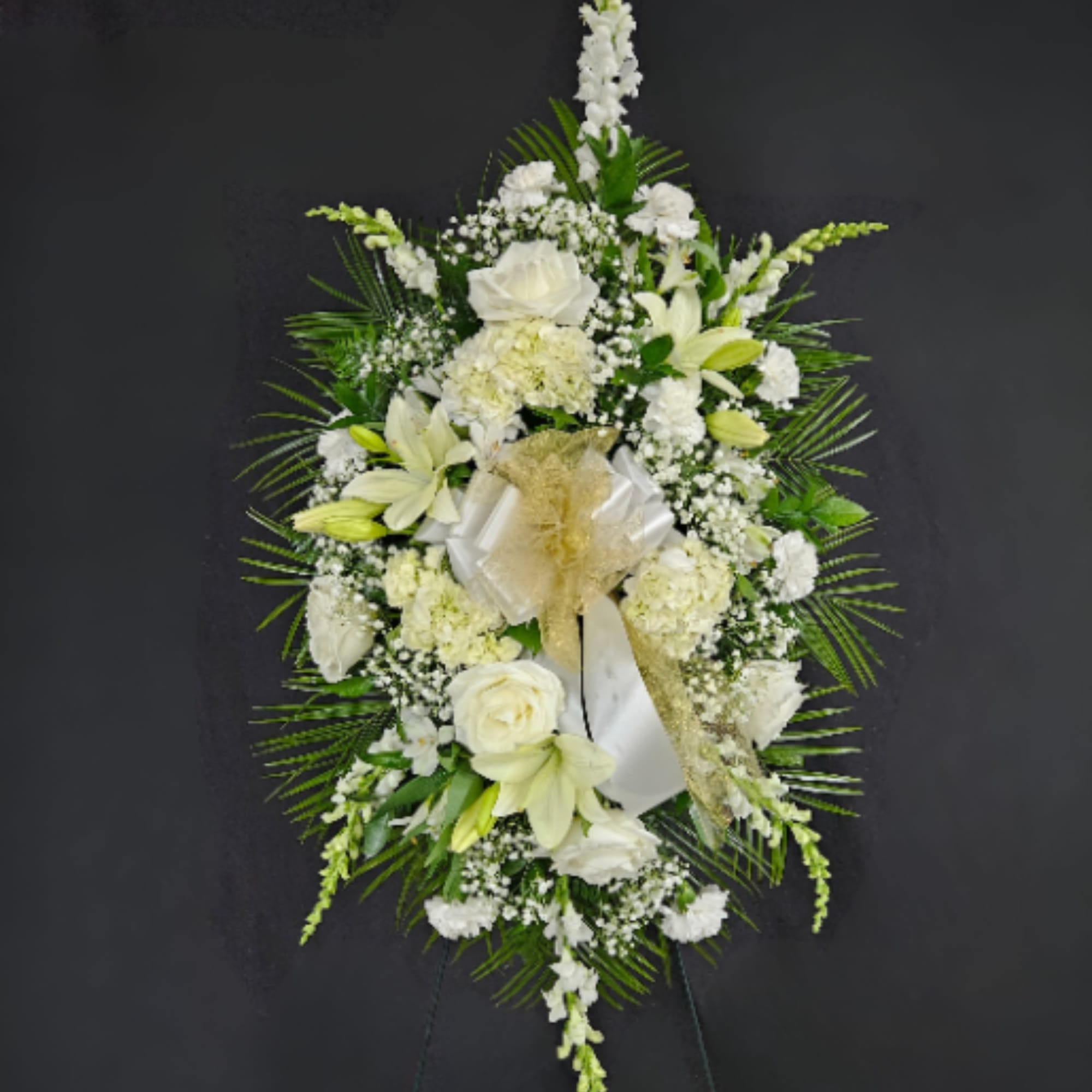 A standing spray of assorted white flowers spread across a bed of