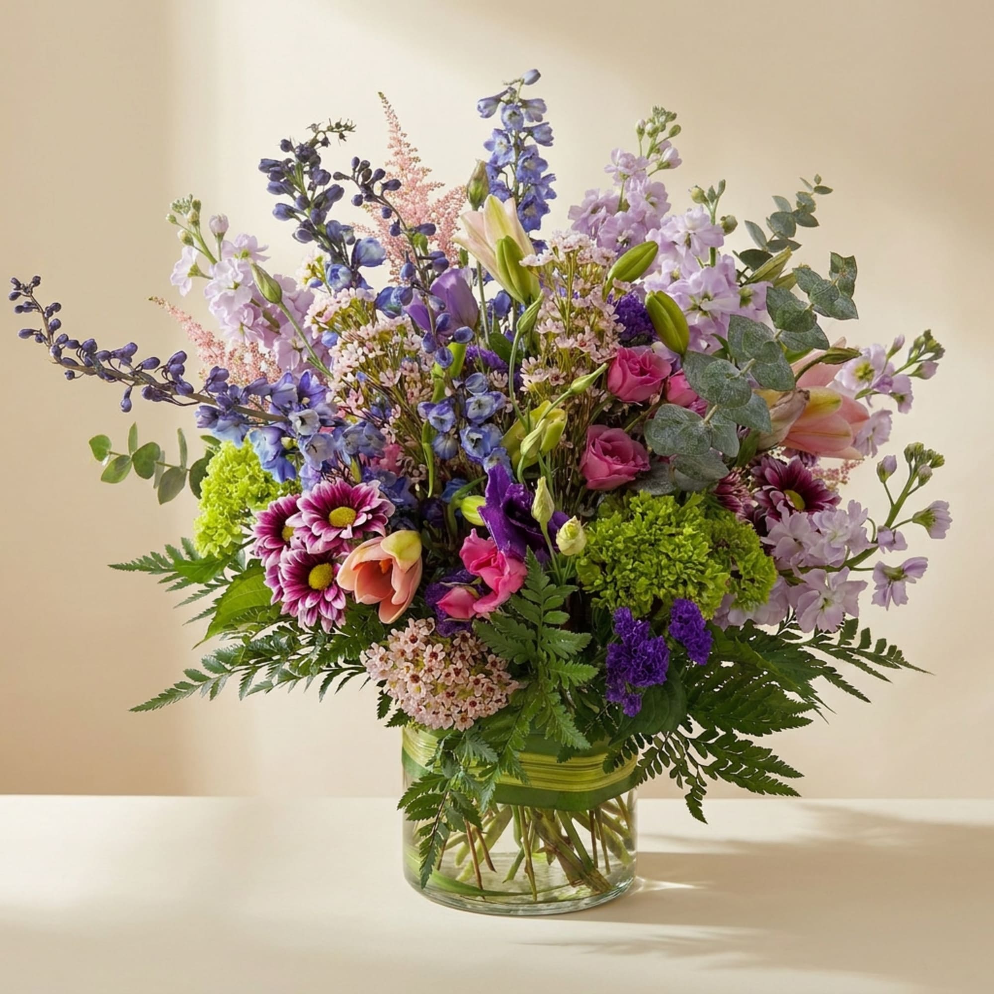 Mixed bouquet of purple, pink, and green flowers in a glass vase