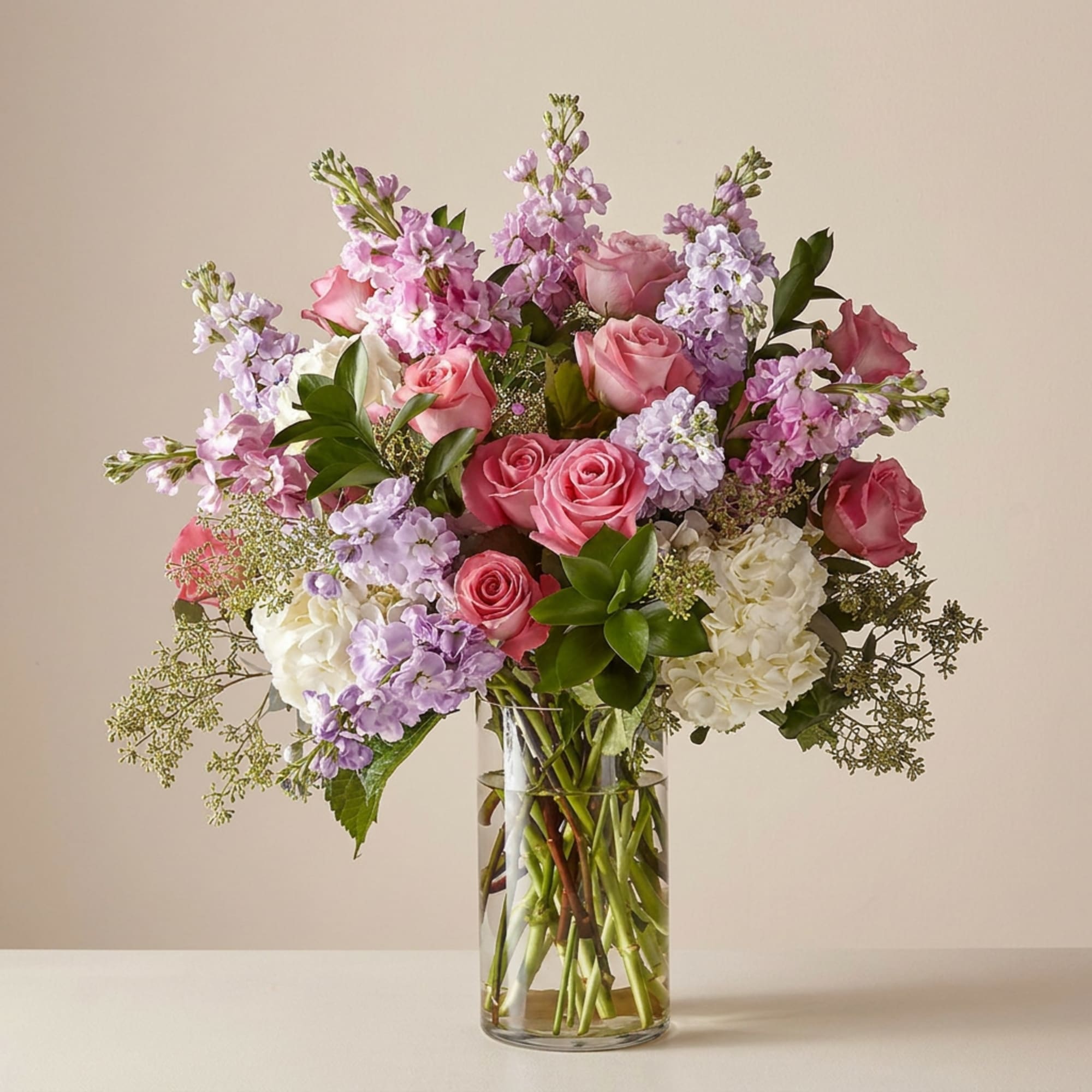 Pink roses and lavender flowers arranged in a clear glass vase