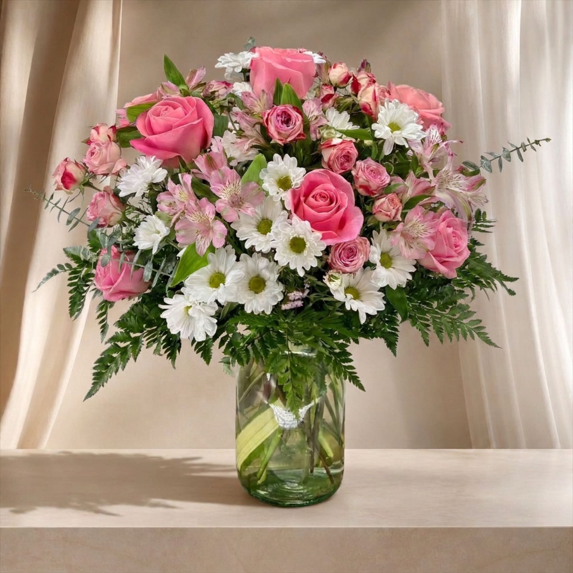 Pink roses and white daisies arranged in a glass vase