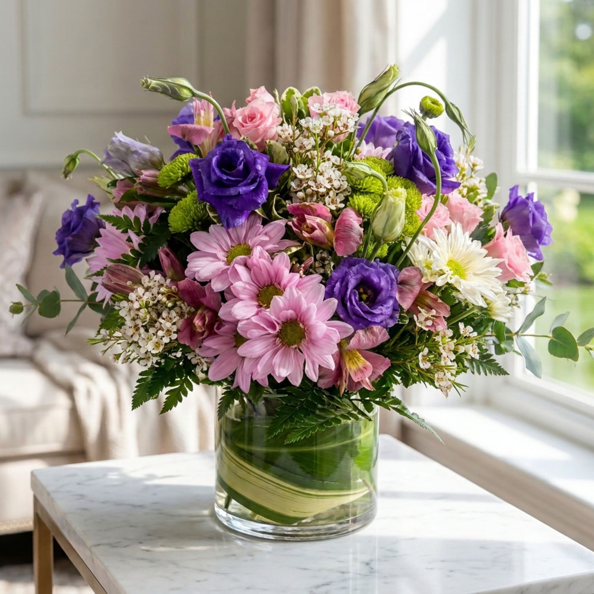 Mixed bouquet of pink and purple flowers in a clear glass vase