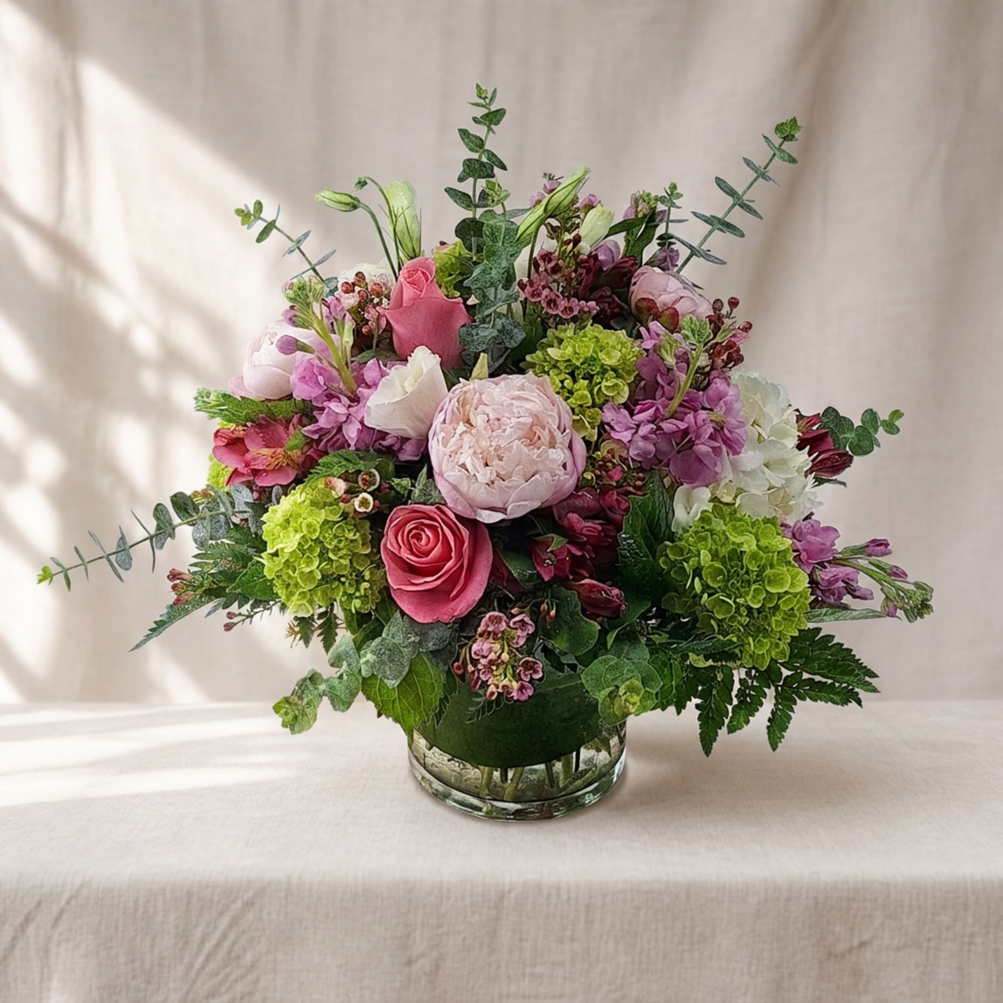 Pink and purple mixed flower arrangement in a clear glass vase