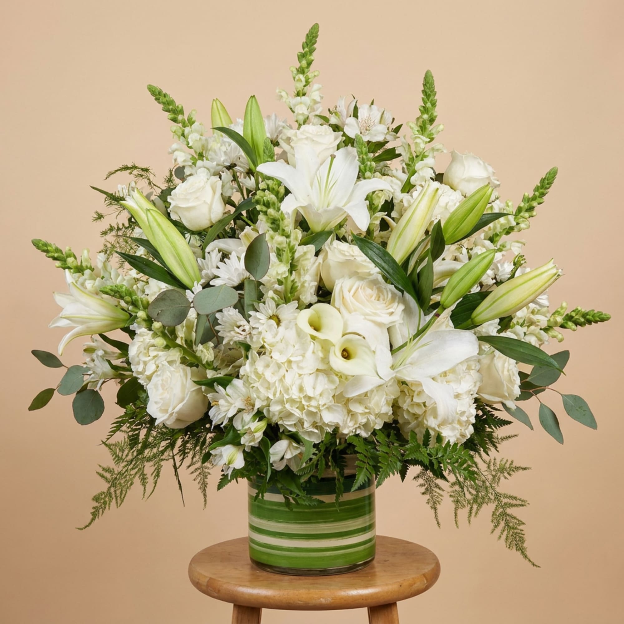 White lilies, roses, and hydrangeas in a green striped vase