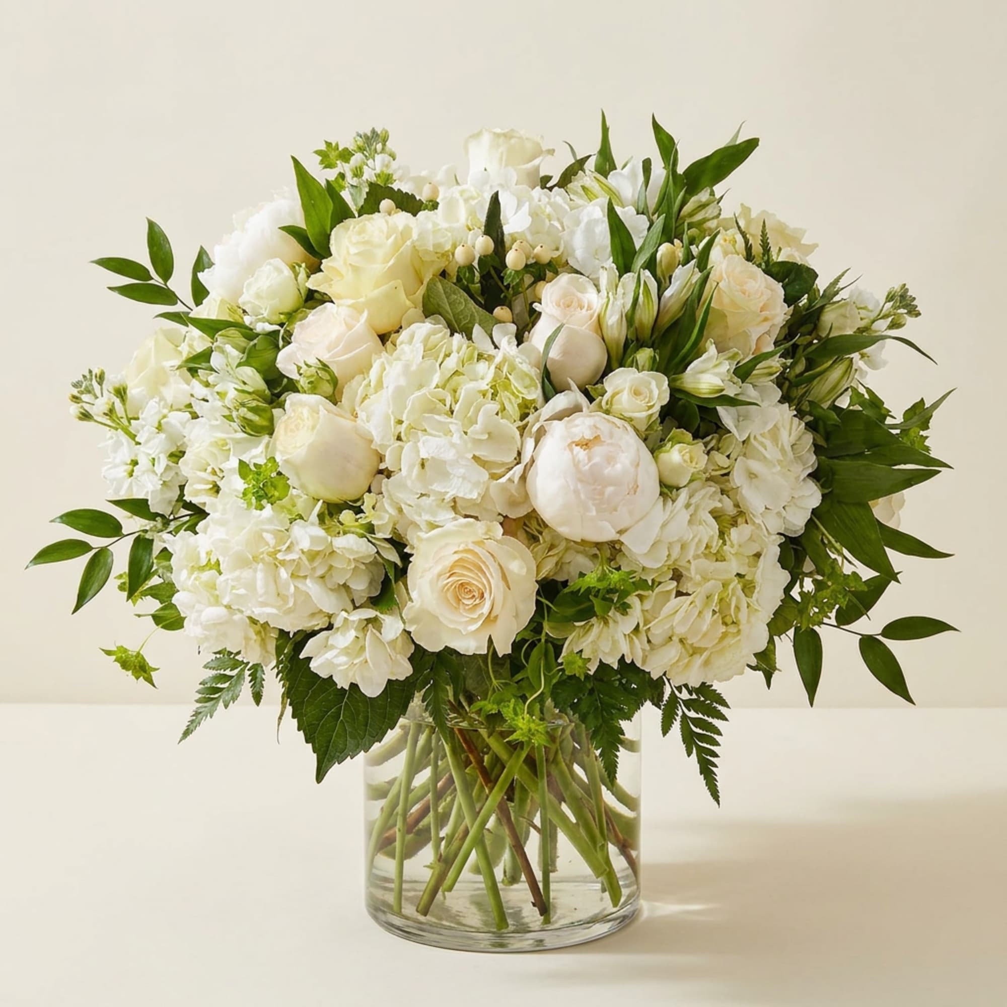 White floral bouquet in a clear glass vase with green foliage