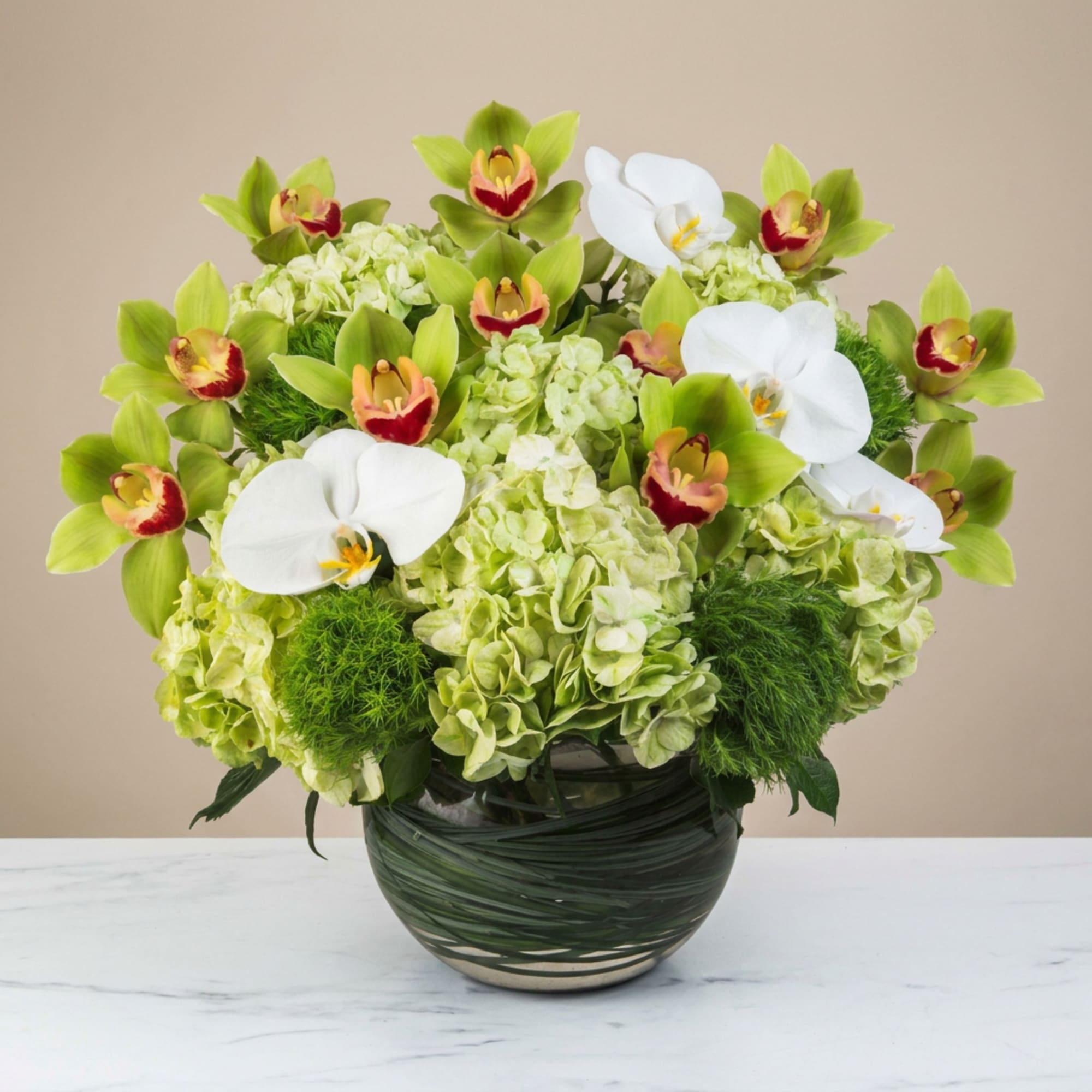Green orchid and hydrangea arrangement in a dark glass vase