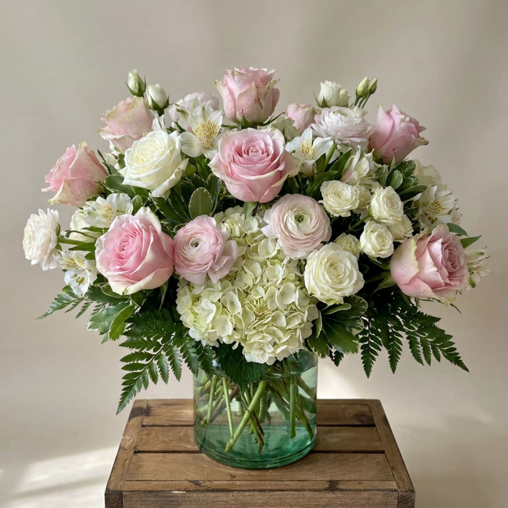 Pink and white roses with white hydrangea in a glass vase