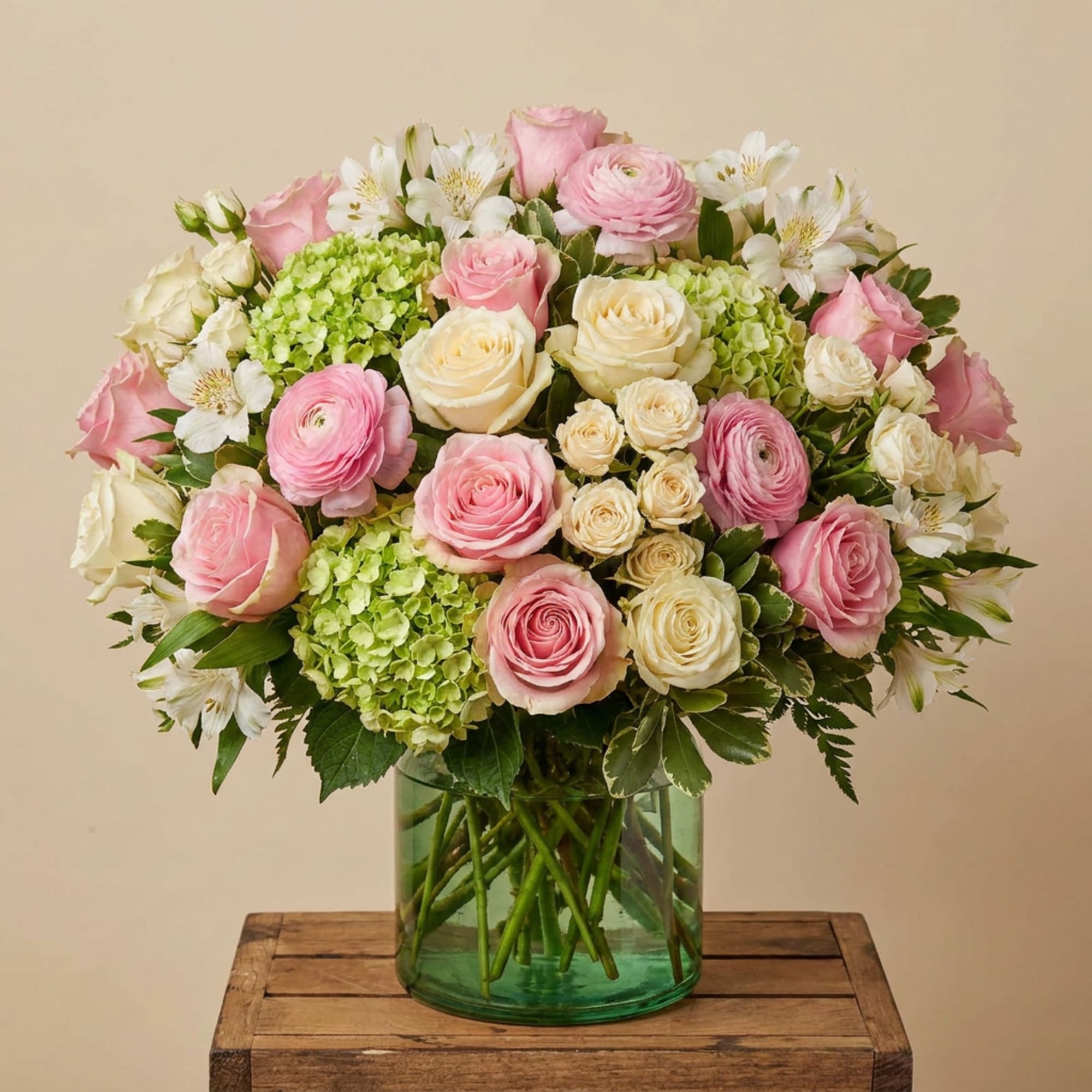 Pink and cream roses with white blooms in a green glass vase