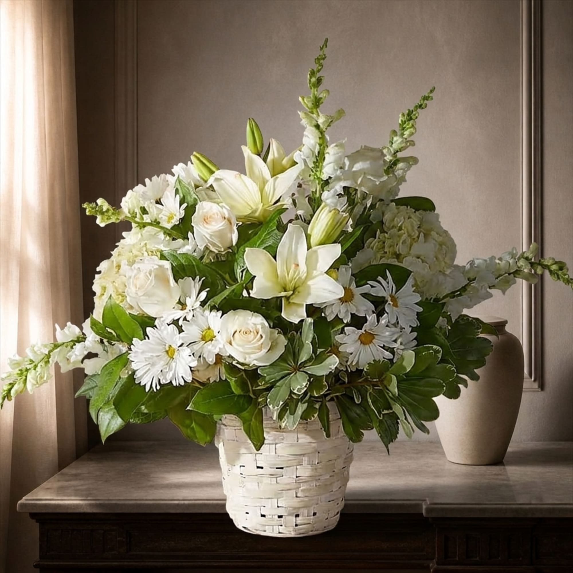 White floral arrangement in a woven basket with lilies, roses, and daisies