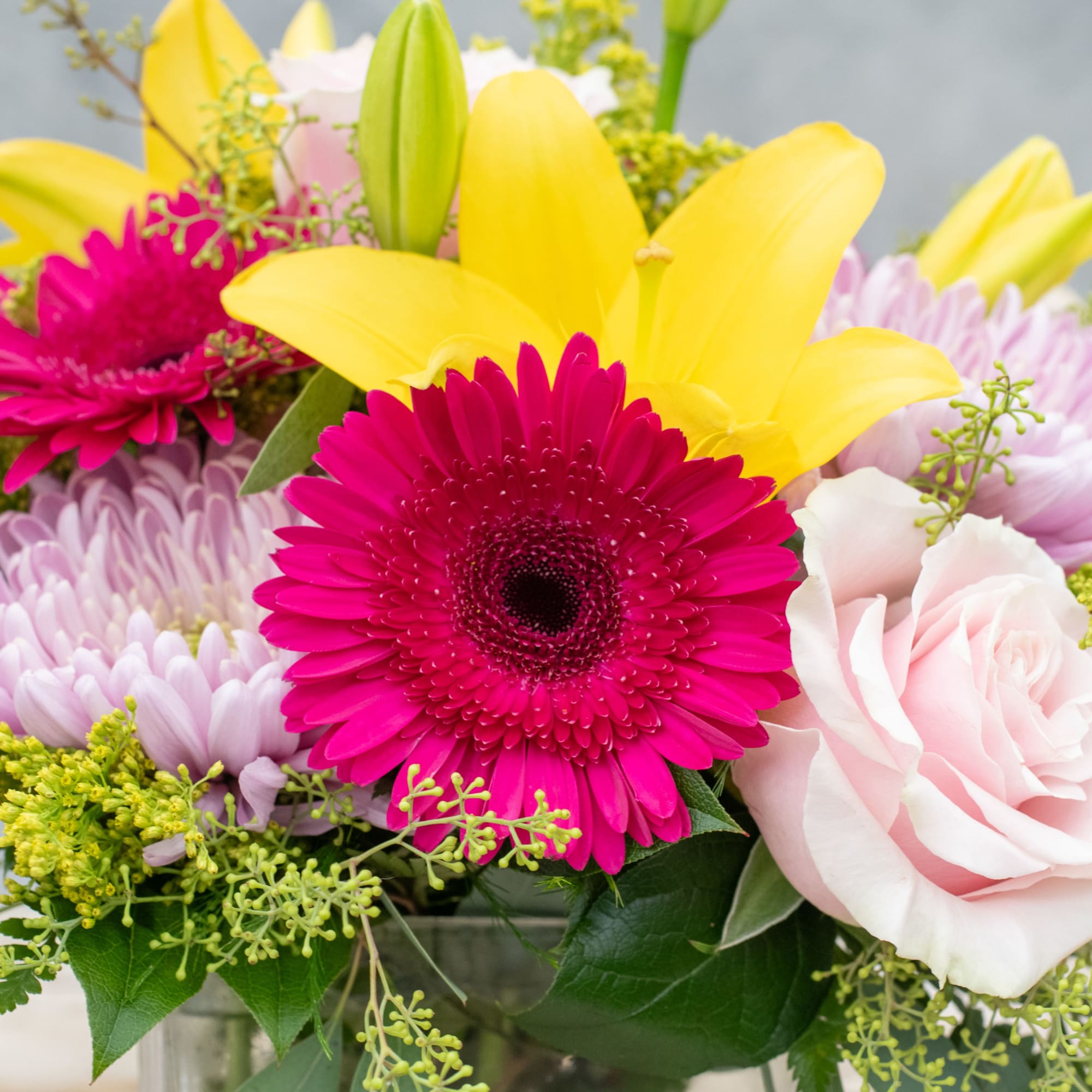 Bright mixed bouquet with yellow lilies, pink gerbera daisies, and pale roses