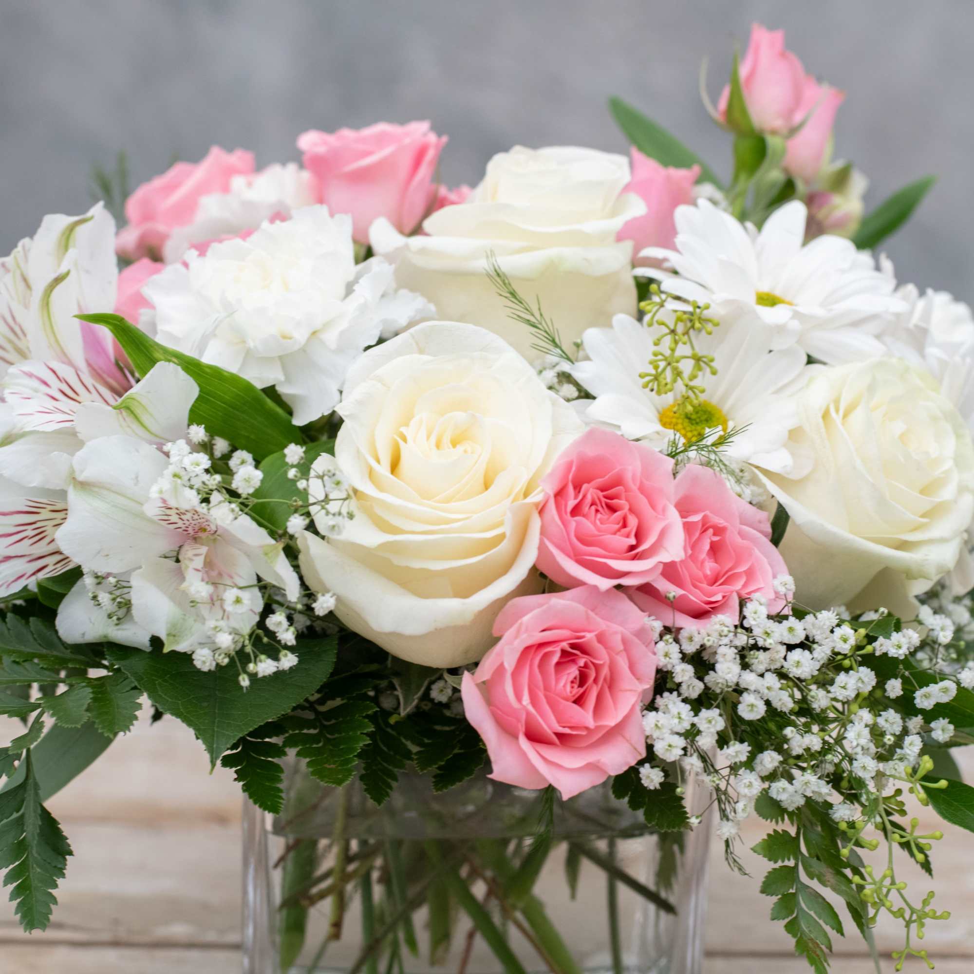 Pink and white rose bouquet with daisies in a clear glass vase