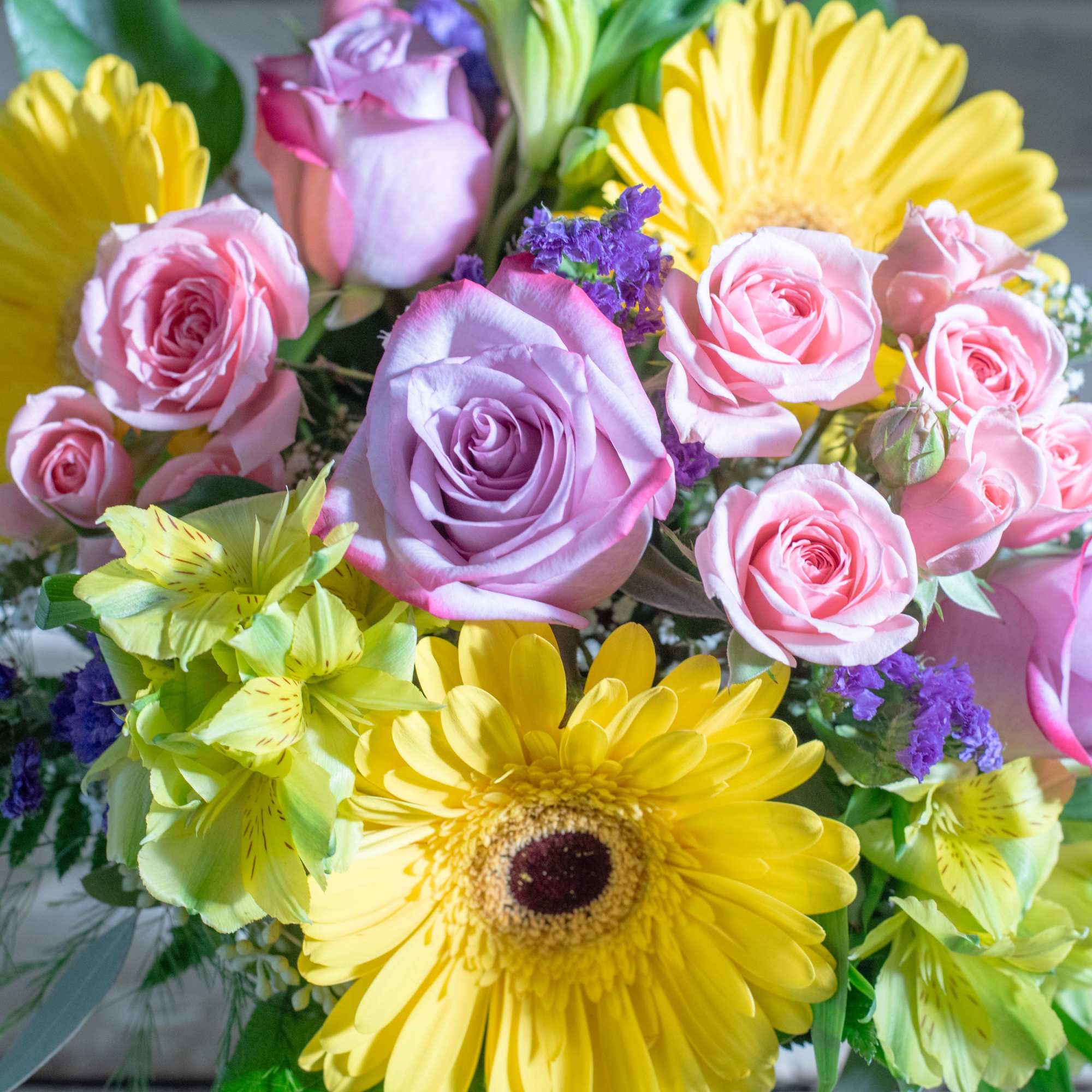 Bouquet of pink and lavender roses with yellow daisies and purple filler flowers